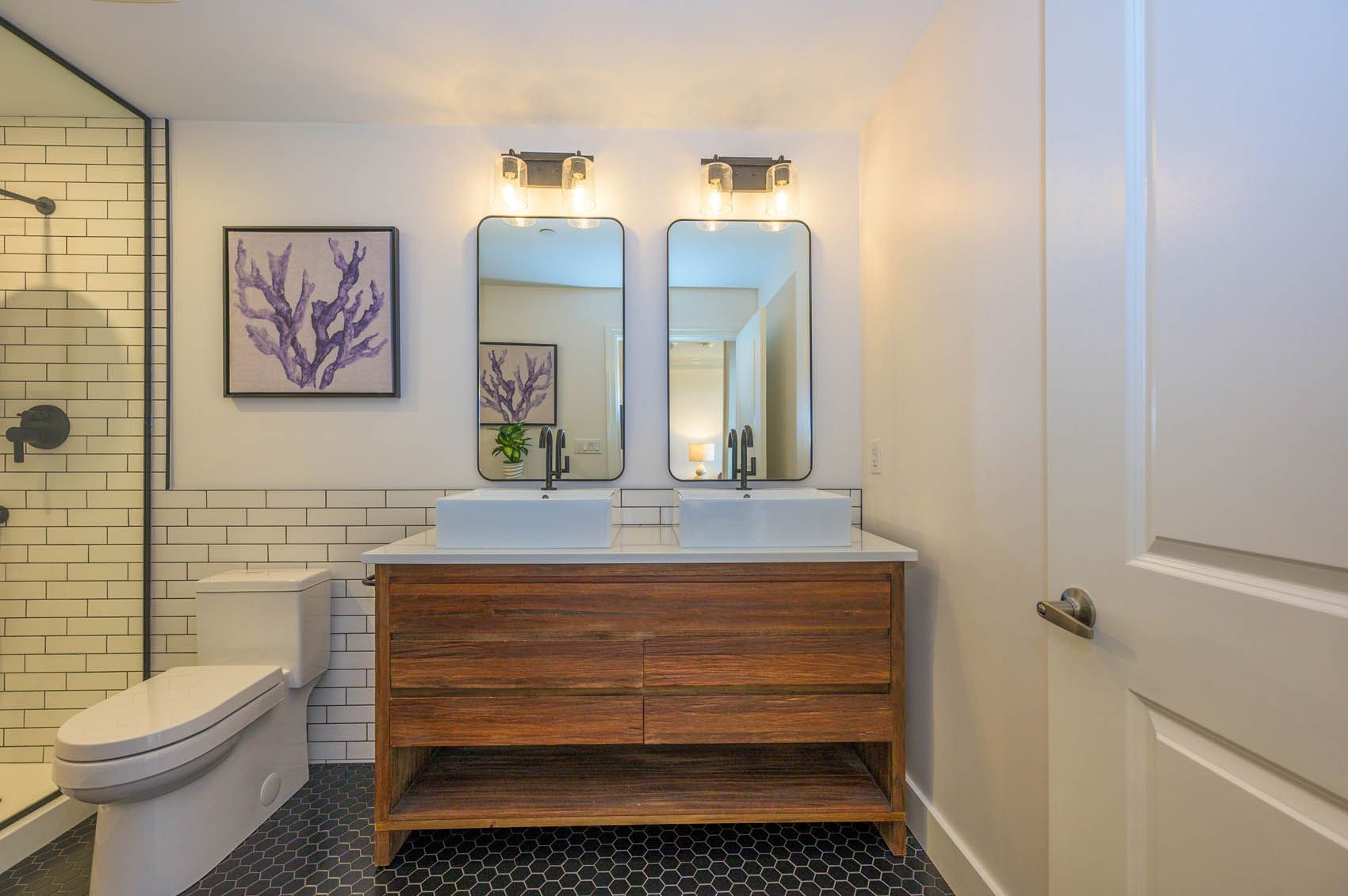 A bathroom with two sinks , a toilet , and a shower.