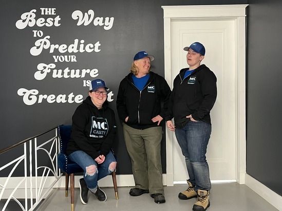 Three people standing in front of a wall that says the best way to predict your future is to create it