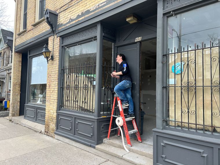 A man is standing on a ladder in front of a building.