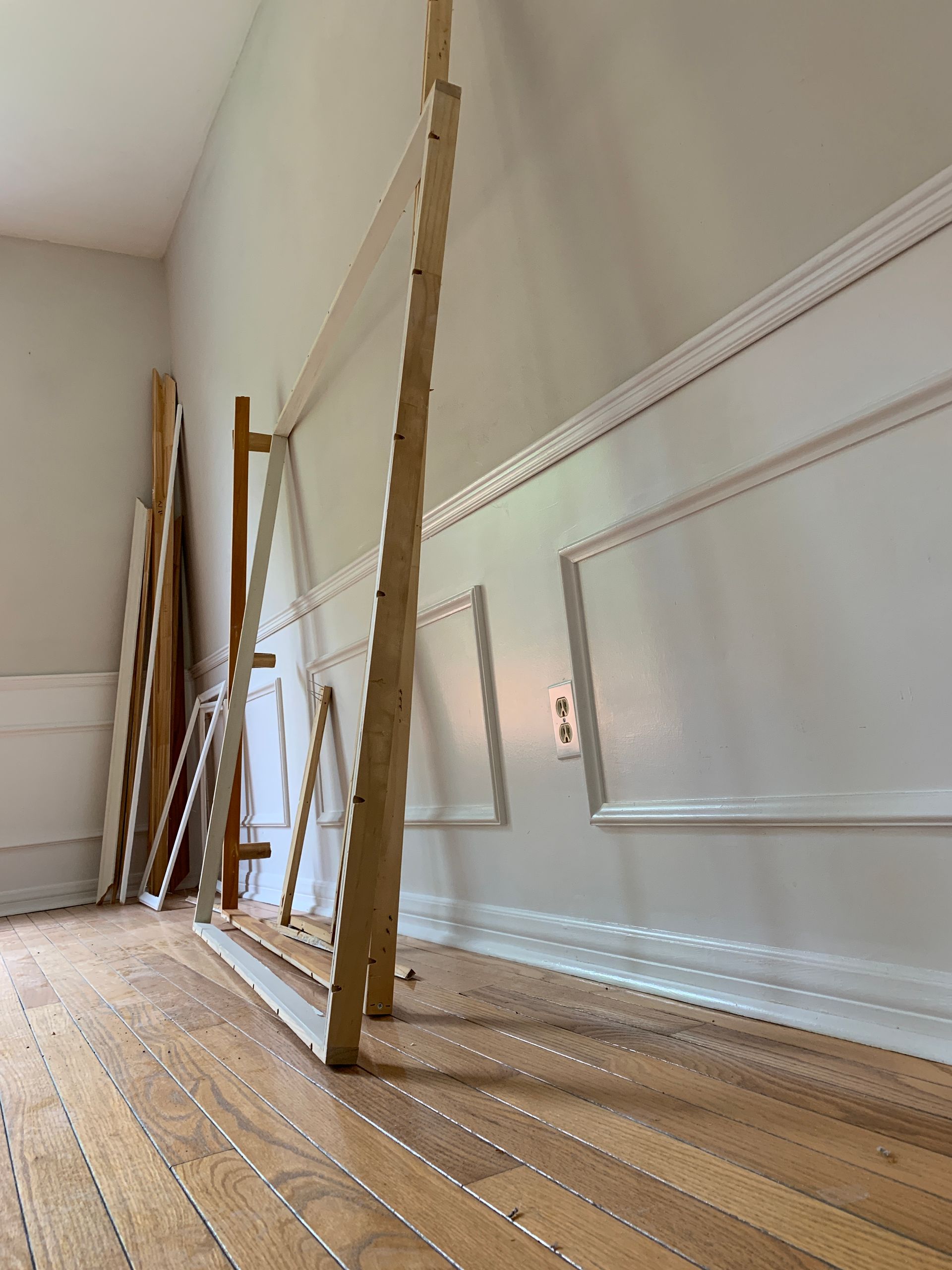 A wooden easel is sitting on a wooden floor in a room.