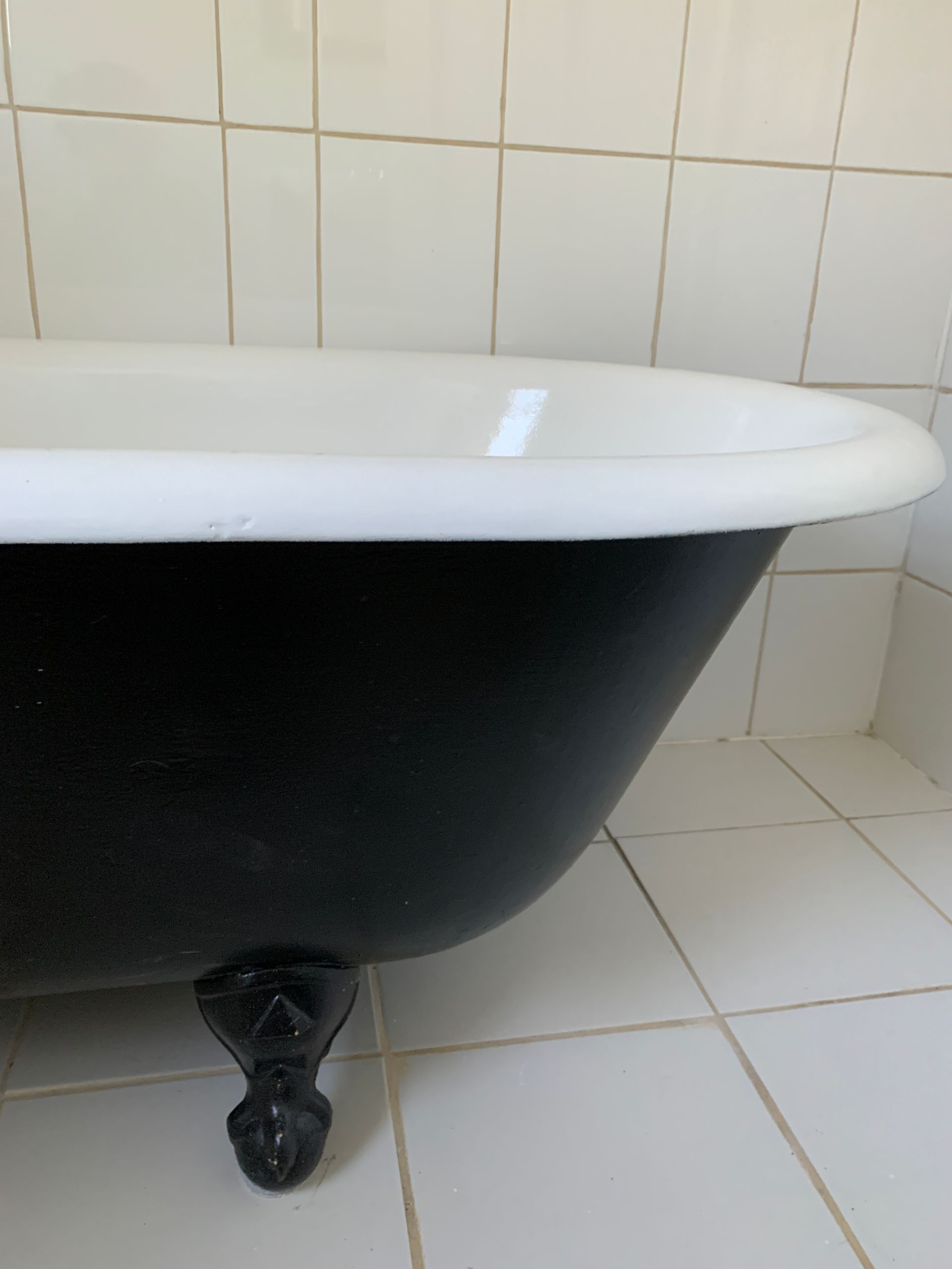 A black bathtub with claw feet in a bathroom