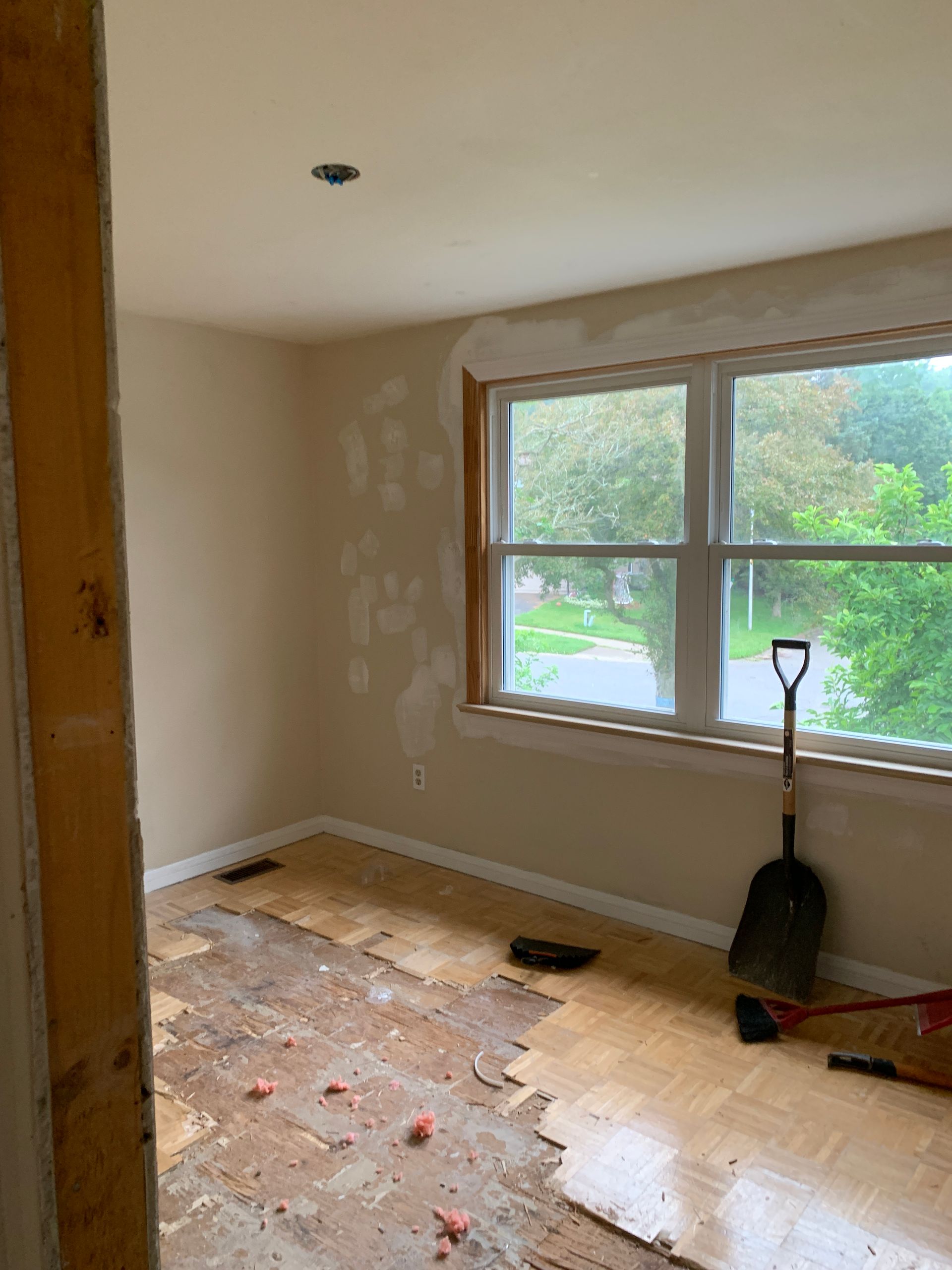 A room with a window and a shovel on the floor.