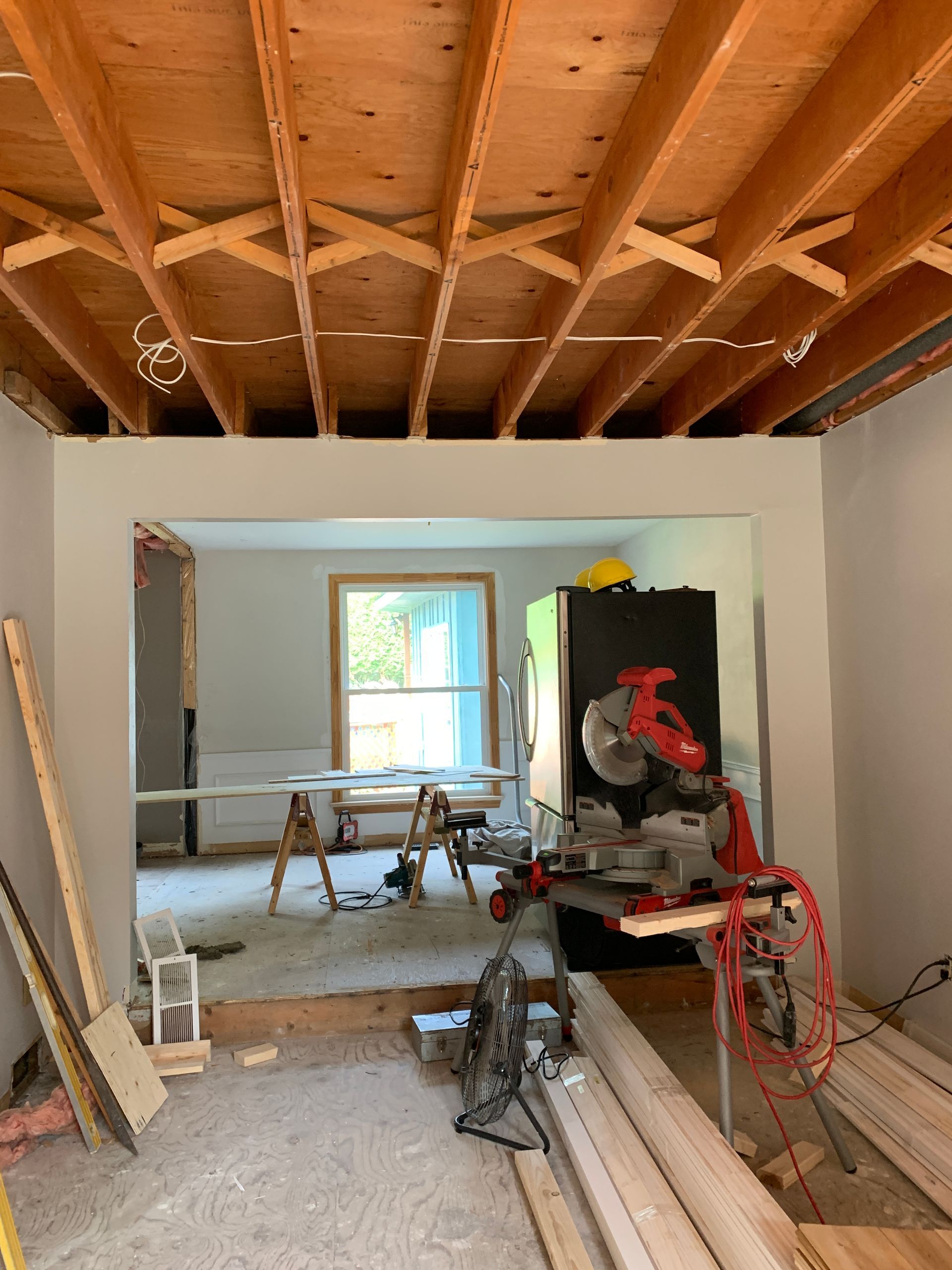 A room under construction with wooden beams and a circular saw.