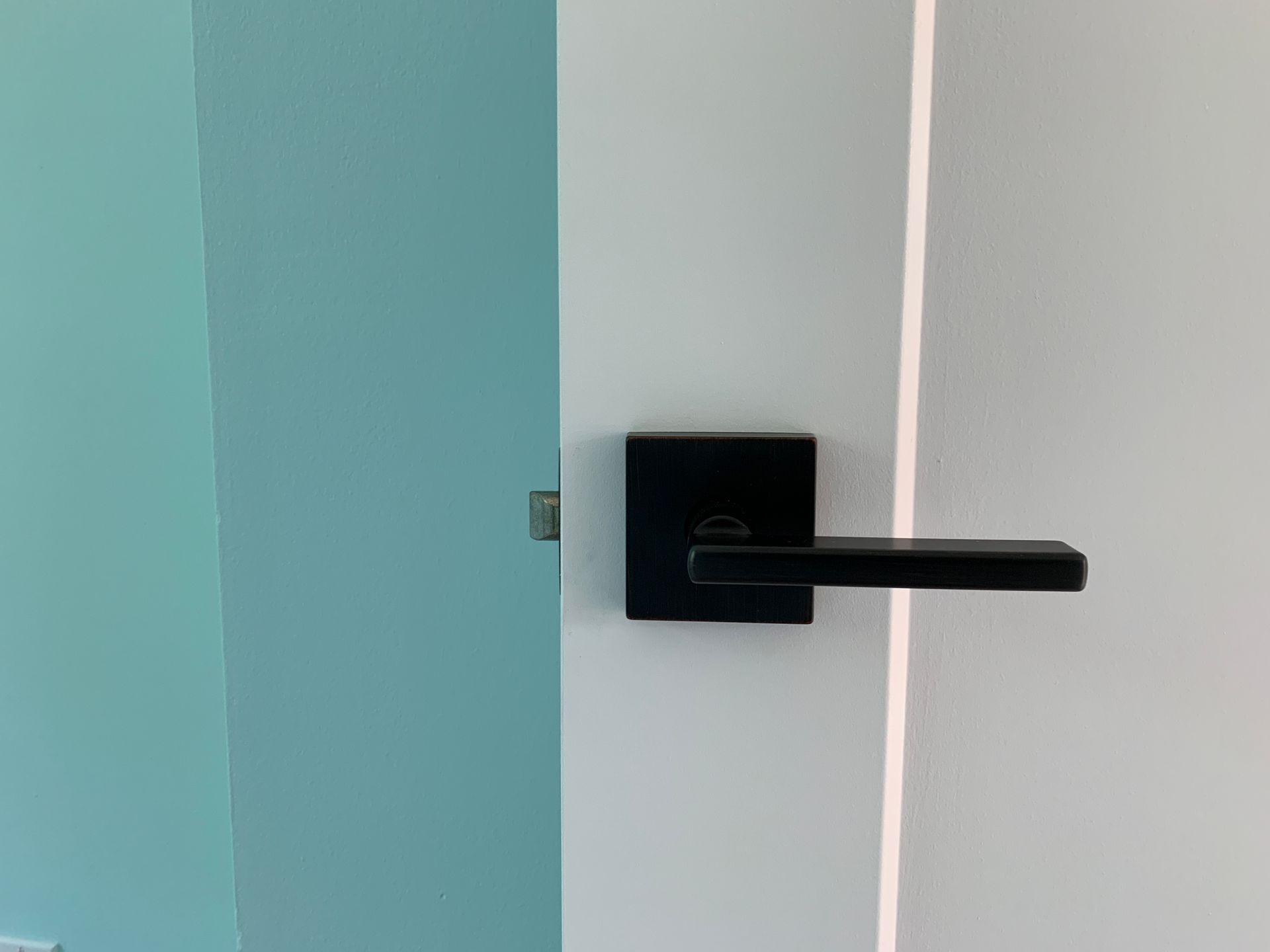 A close up of a black door handle on a white door.