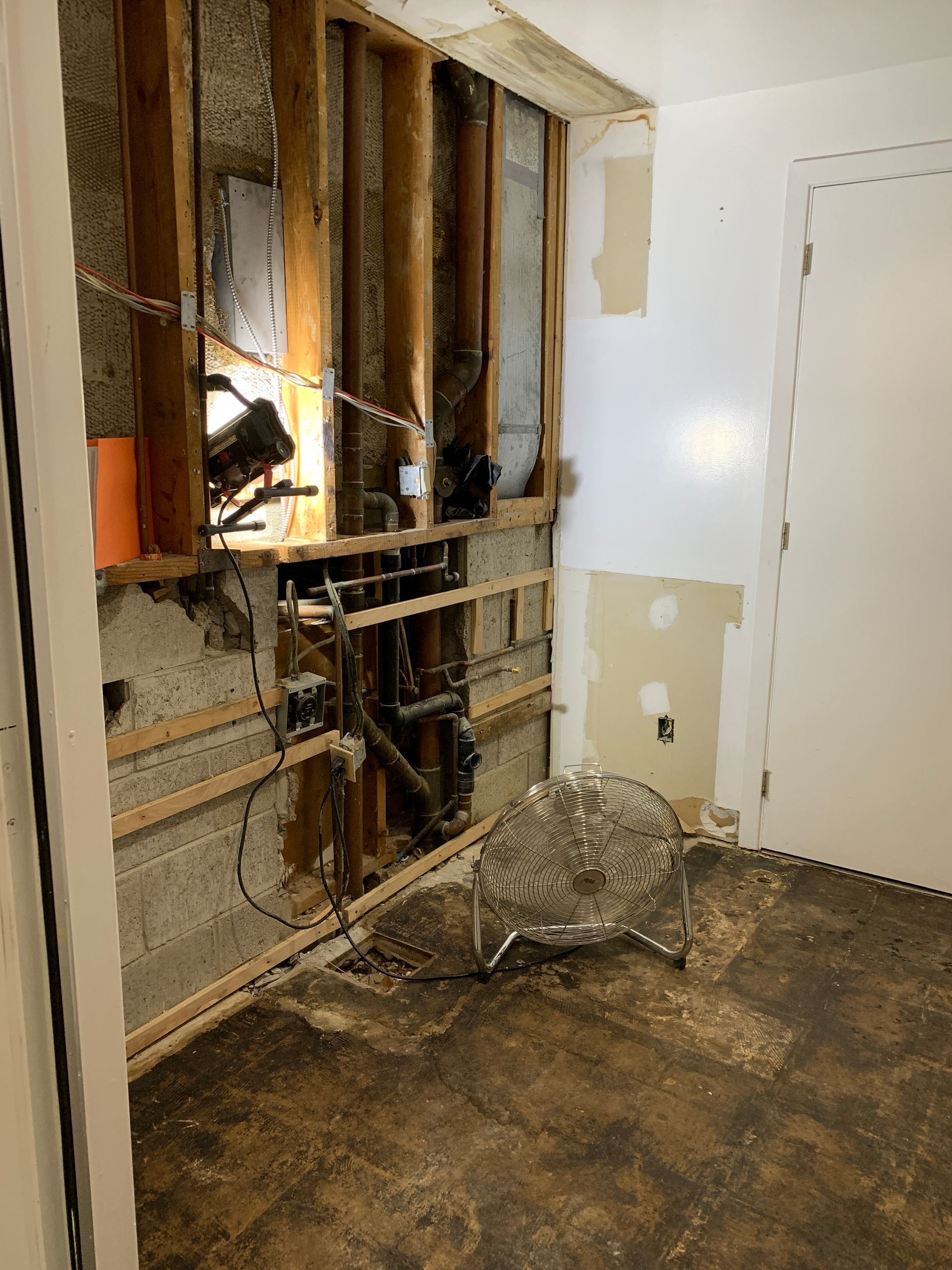 A room with wooden walls and a fan on the floor.