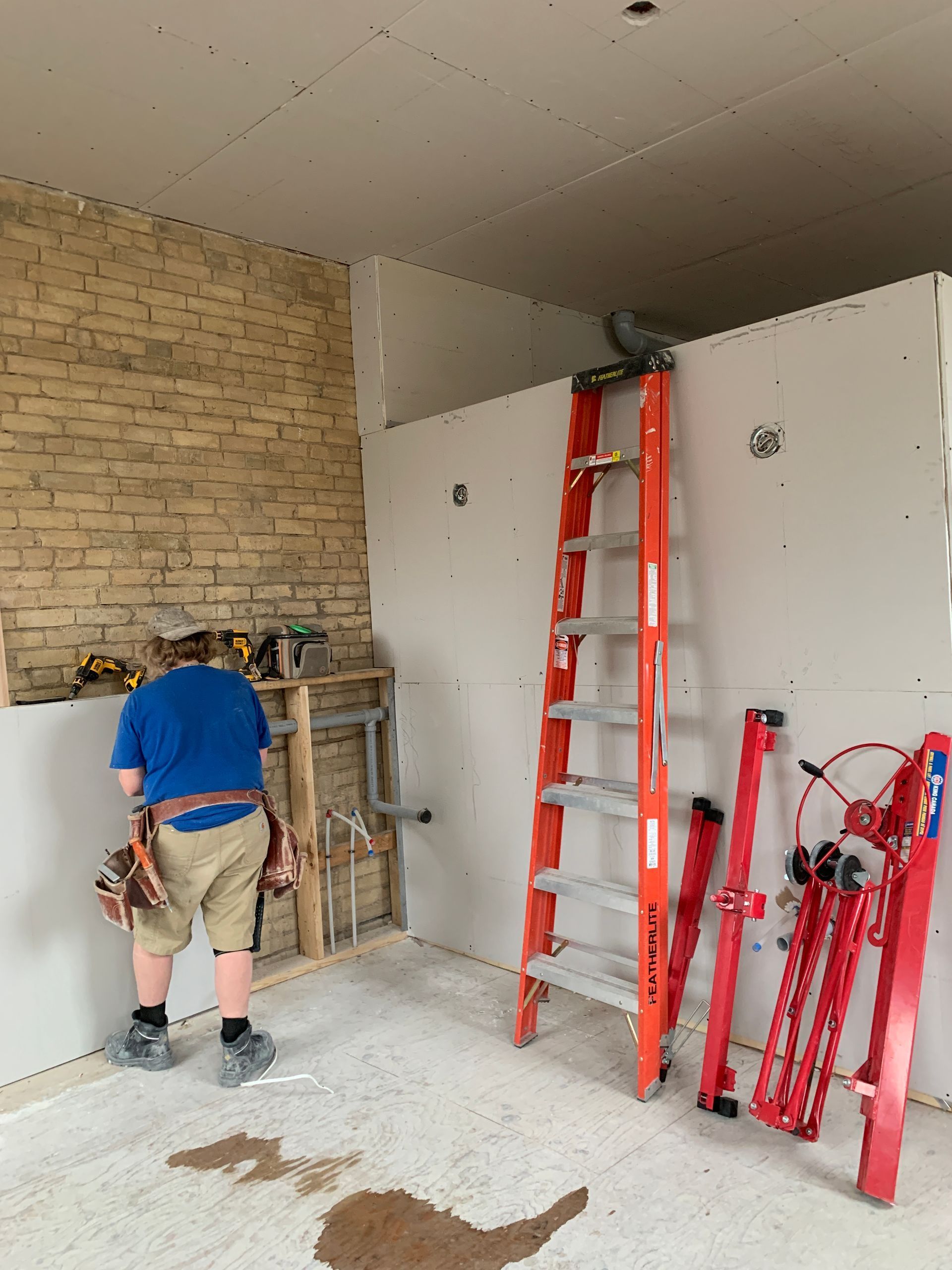 Two construction workers are working on the ceiling of a building.