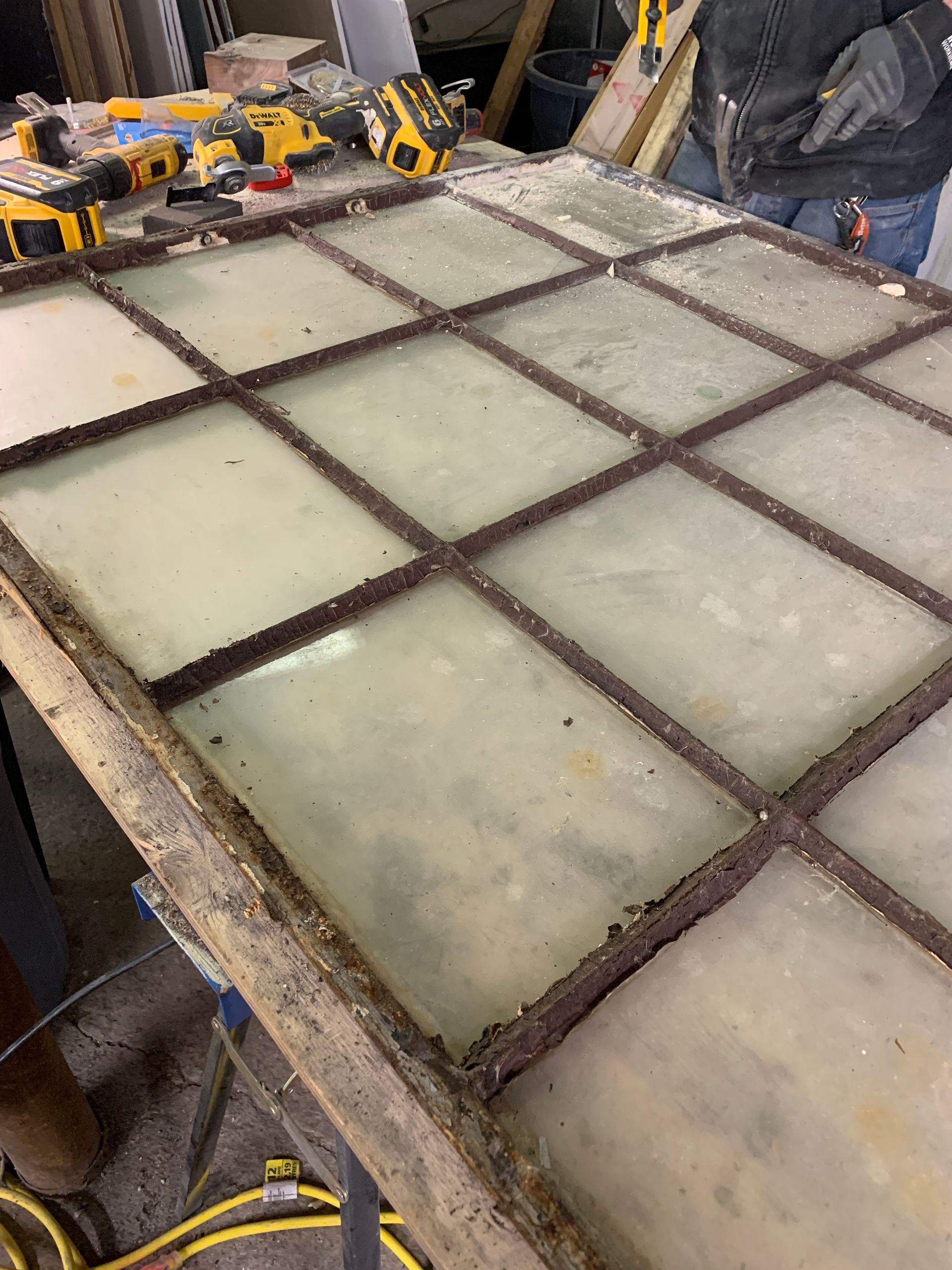 A person is working on a stained glass window in a workshop.