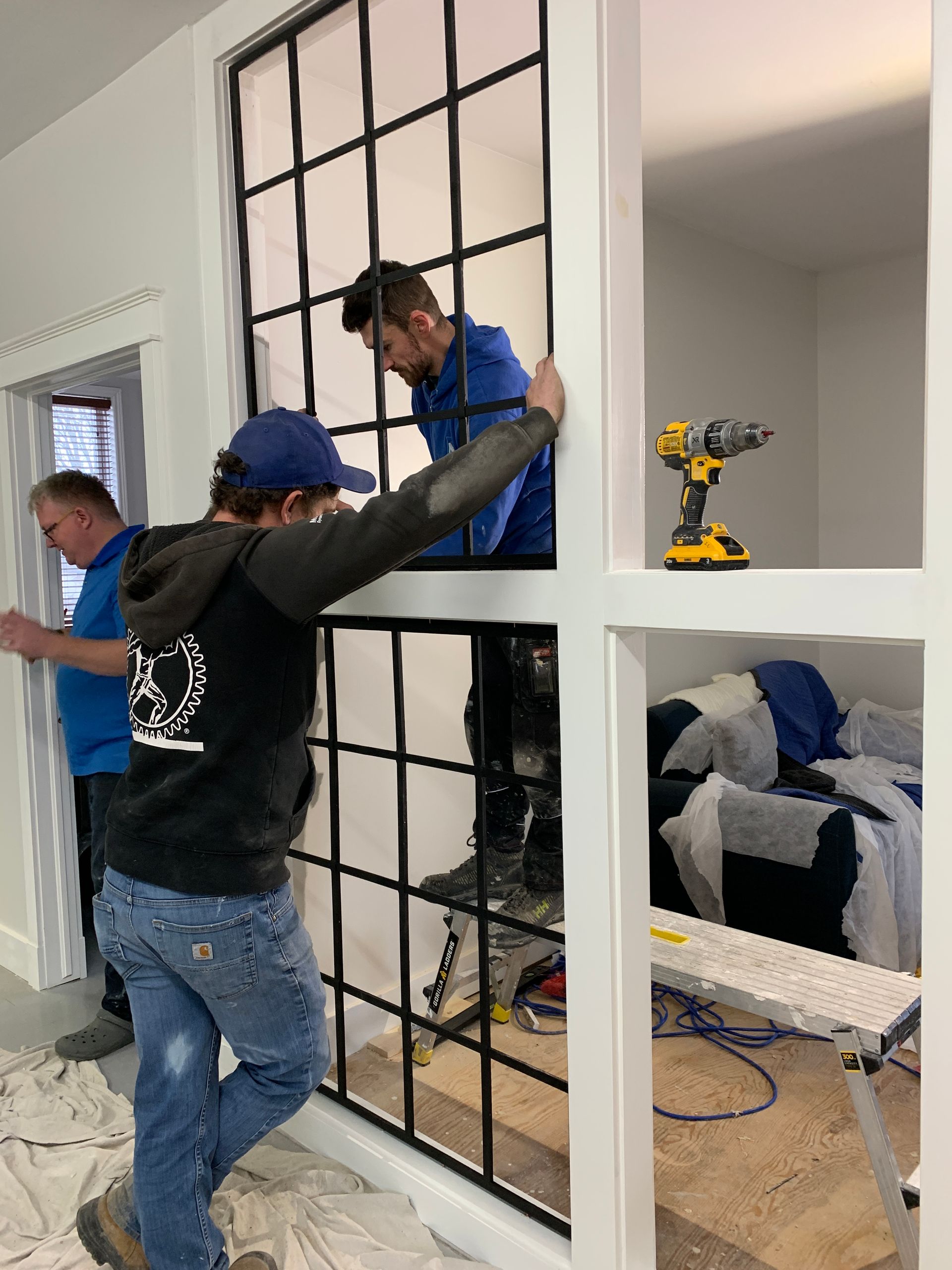 A group of men are working on a window in a room.