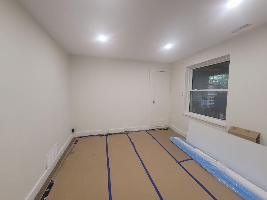 A basement with a wooden floor and white walls.