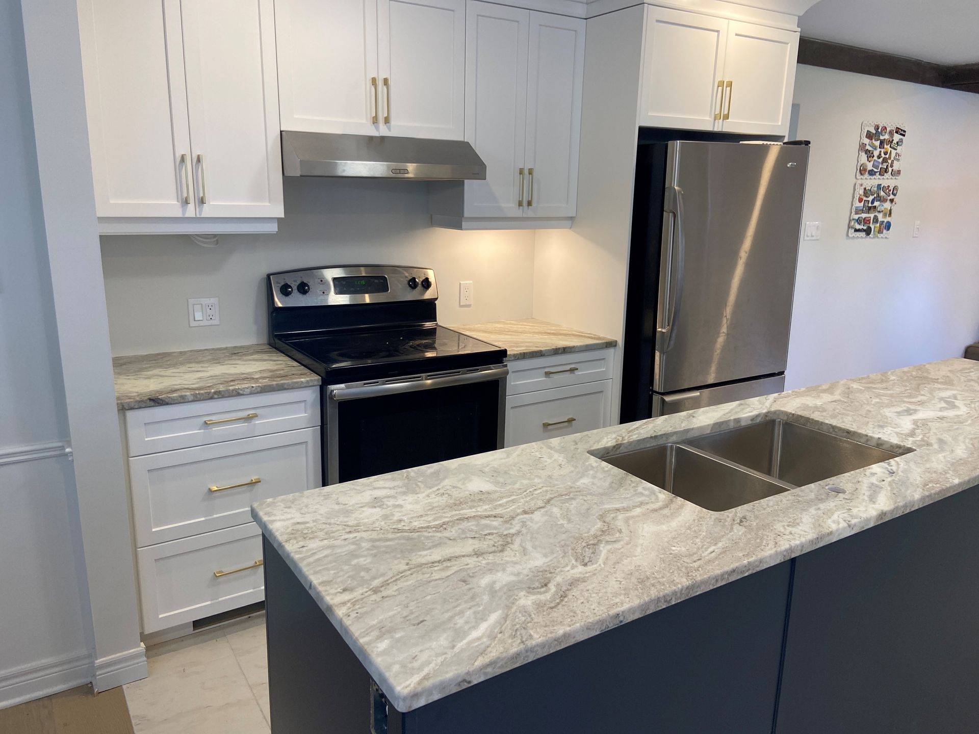 A kitchen with a stove , refrigerator , sink and white cabinets.