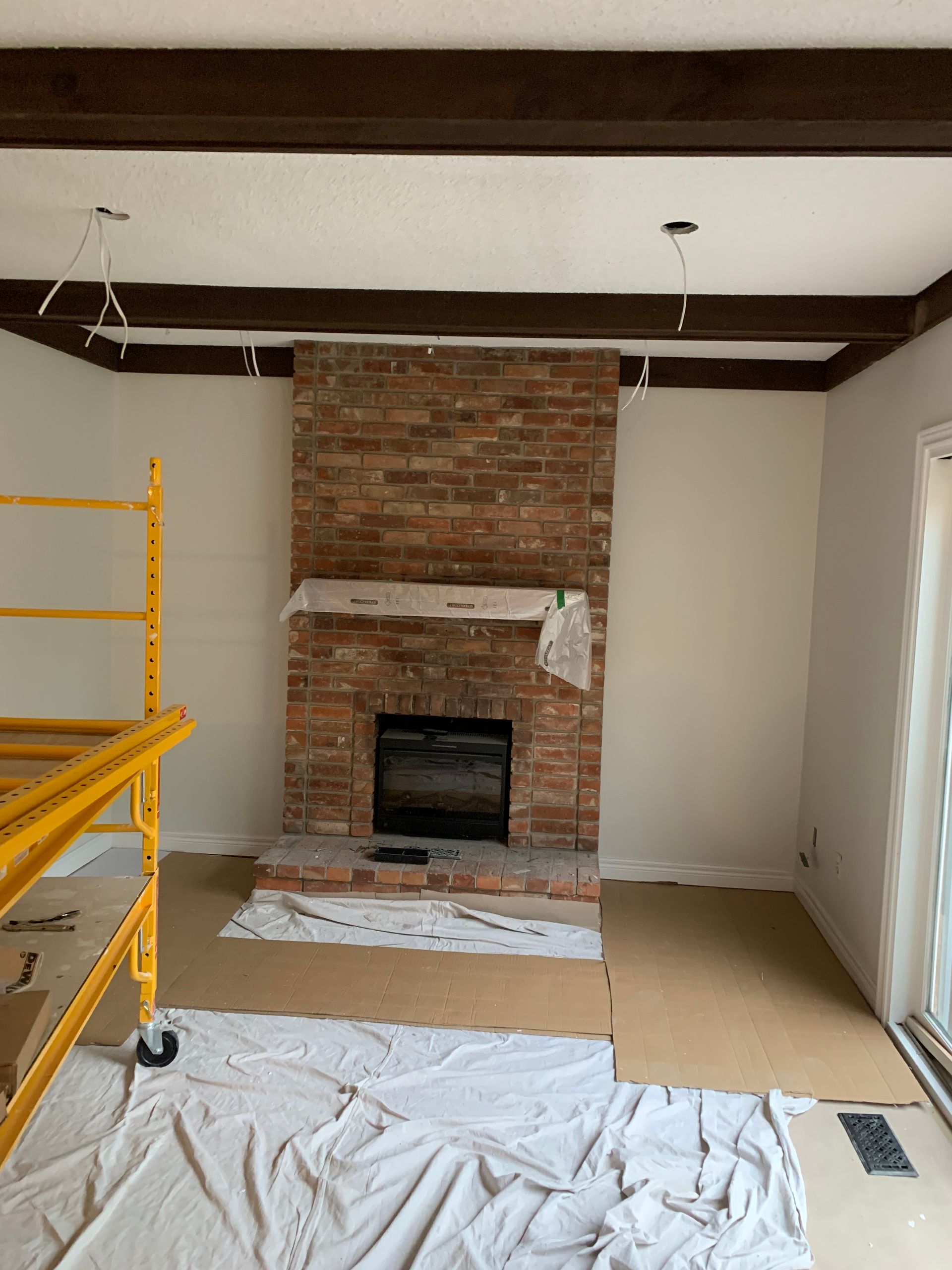 A living room with a brick fireplace and a yellow scaffolding.