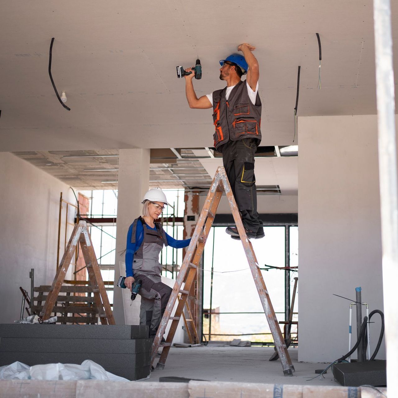 A man standing on a ladder working on a ceiling