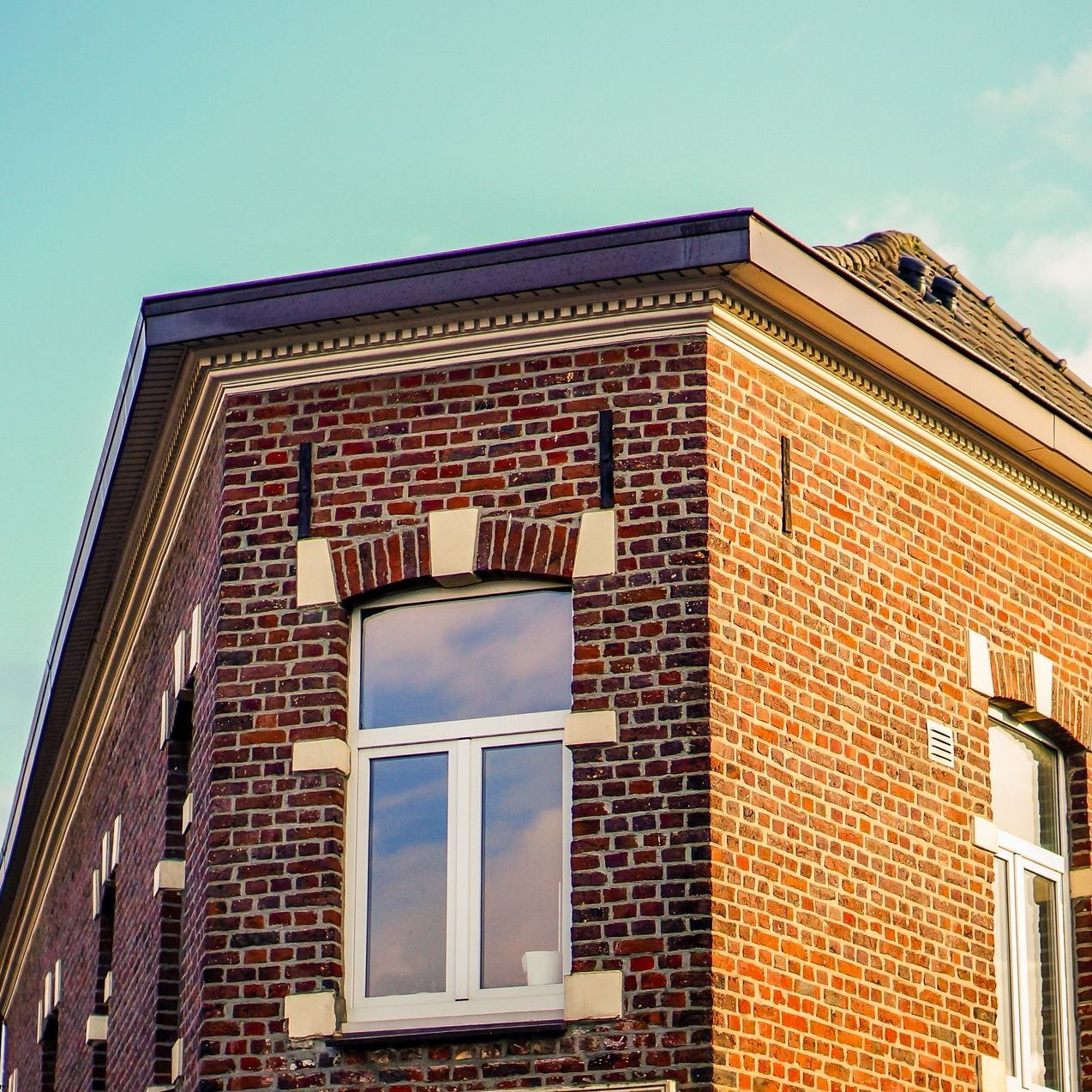 A red brick building with white windows and a blue sky in the background.