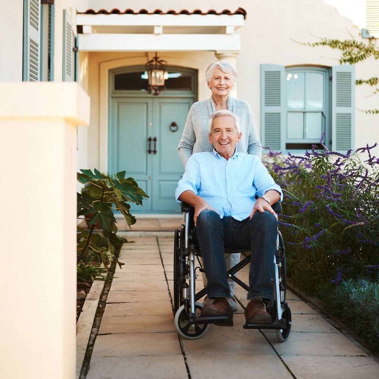 A man in a wheelchair is being pushed by a woman