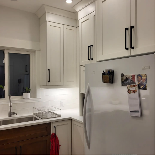 A kitchen with white cabinets and a white refrigerator