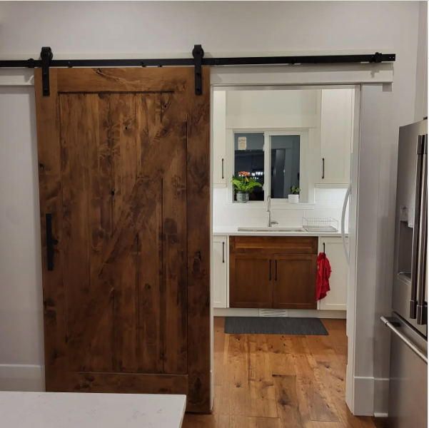 A kitchen with a sliding barn door leading to a kitchen.