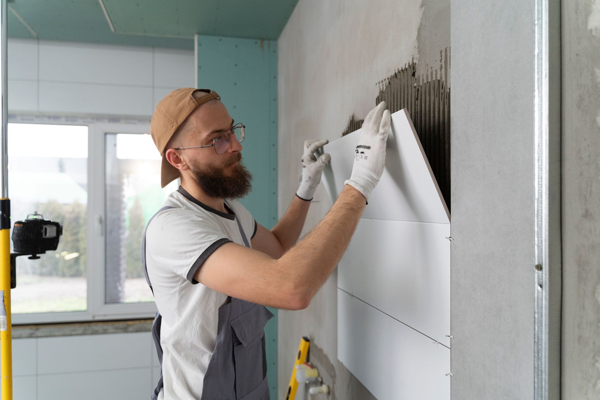 A man is installing tiles on a wall.