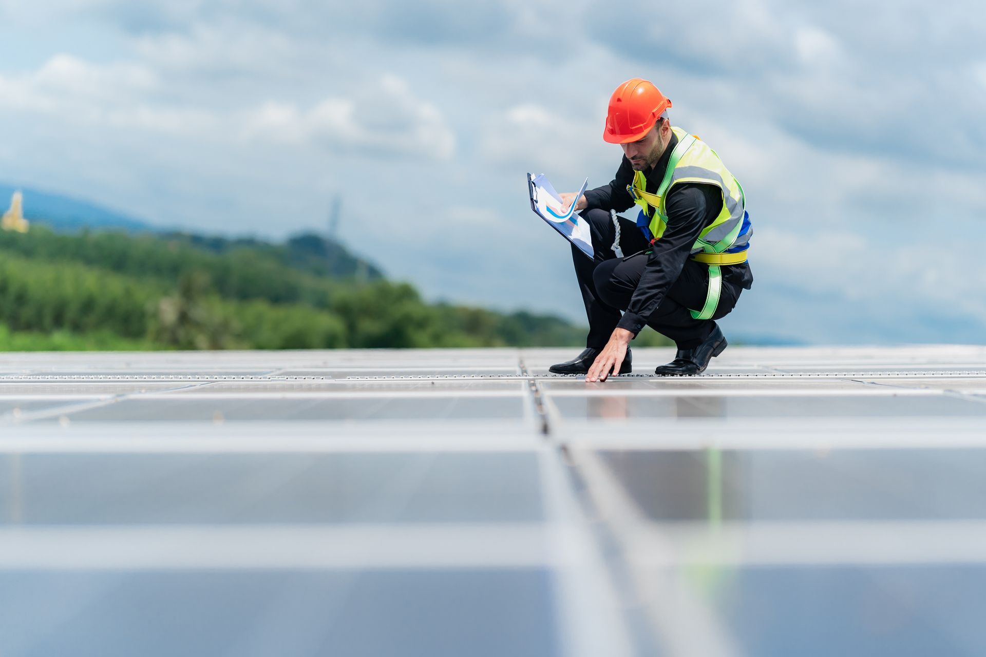 A man is kneeling down on top of a solar panel.