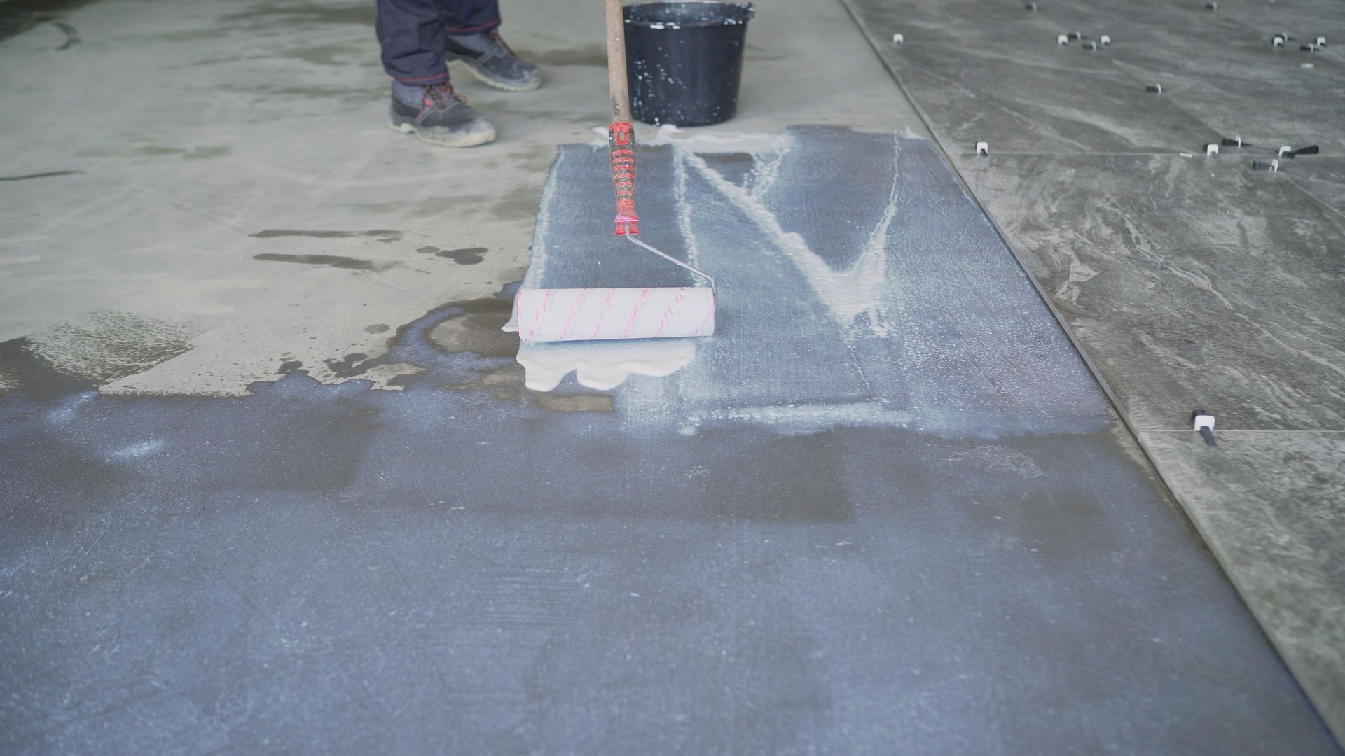 A man in a blue shirt is working on a wooden post with white concrete sealant