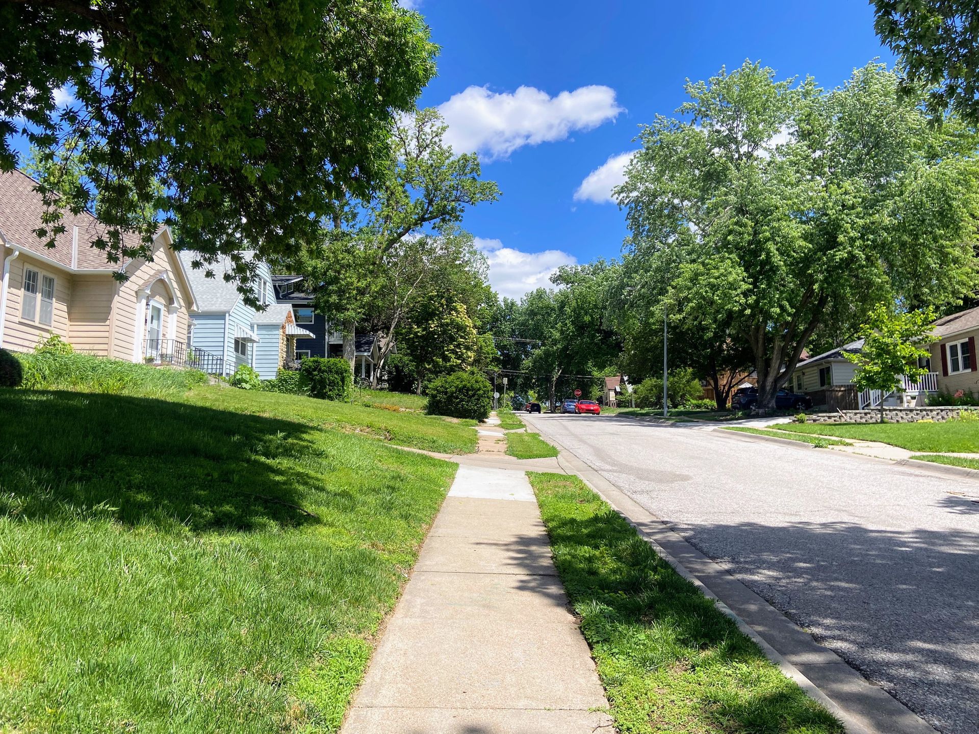A sidewalk in a residential neighborhood with houses and trees