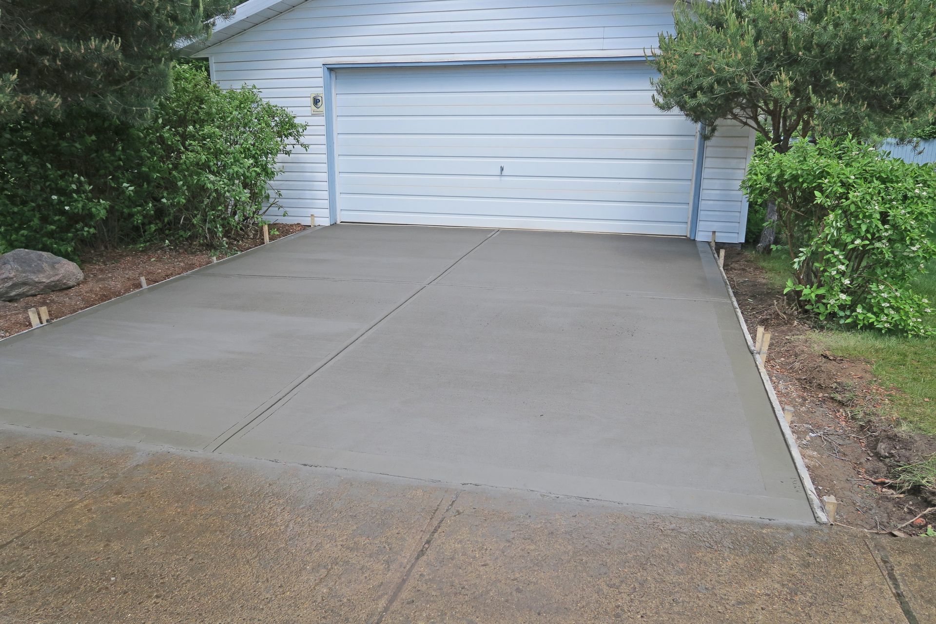 A concrete driveway is being built in front of a garage