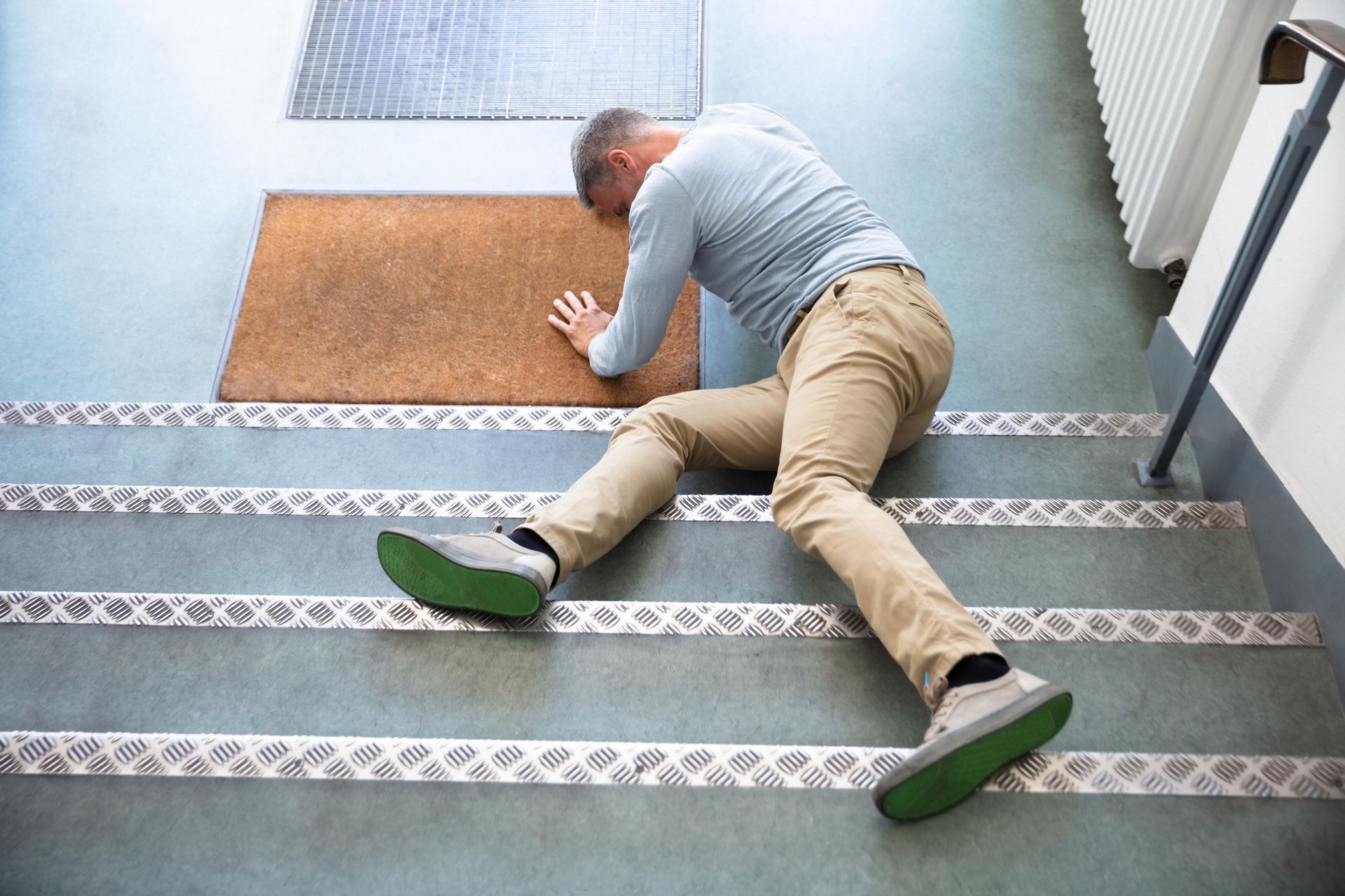 A man is laying on the floor after falling down the stairs.