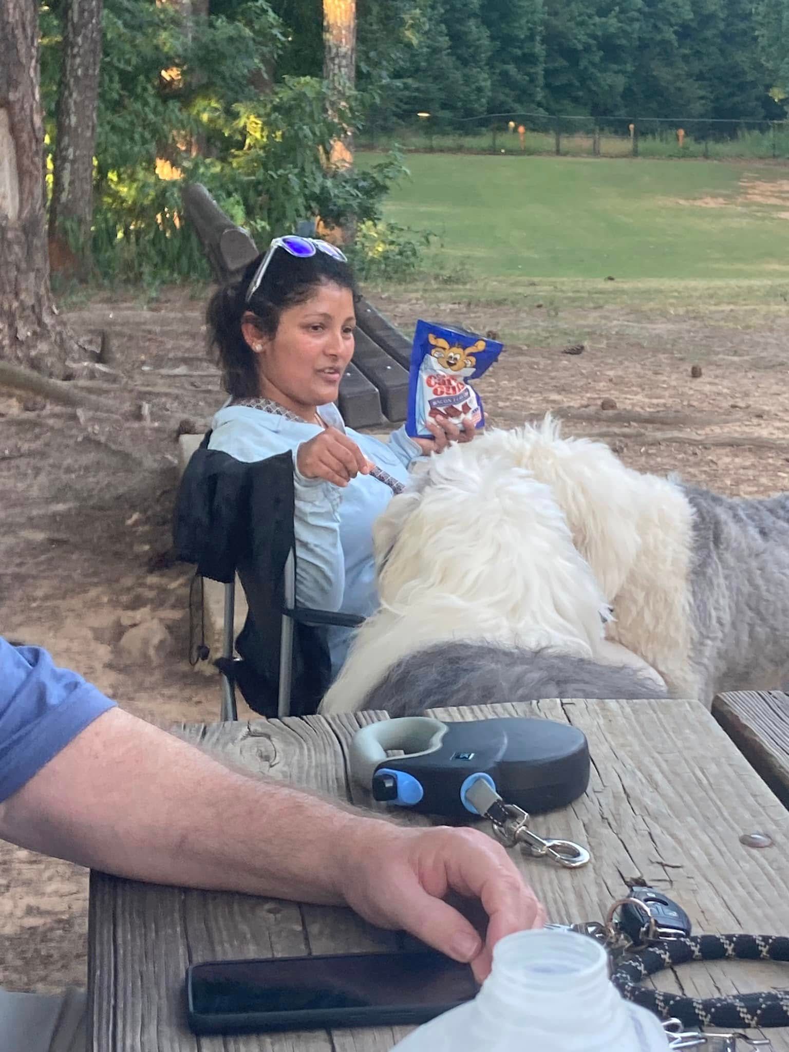 A woman is sitting at a picnic table with a dog.