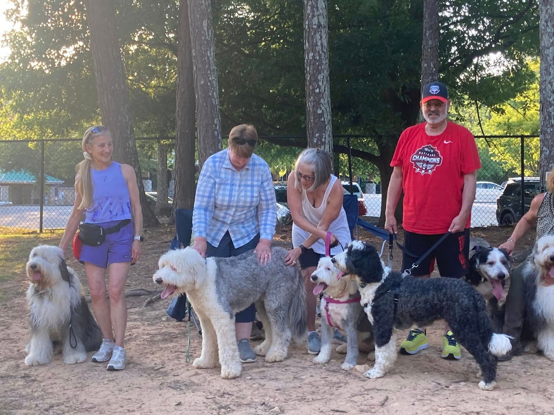 A group of people standing next to each other with their dogs.