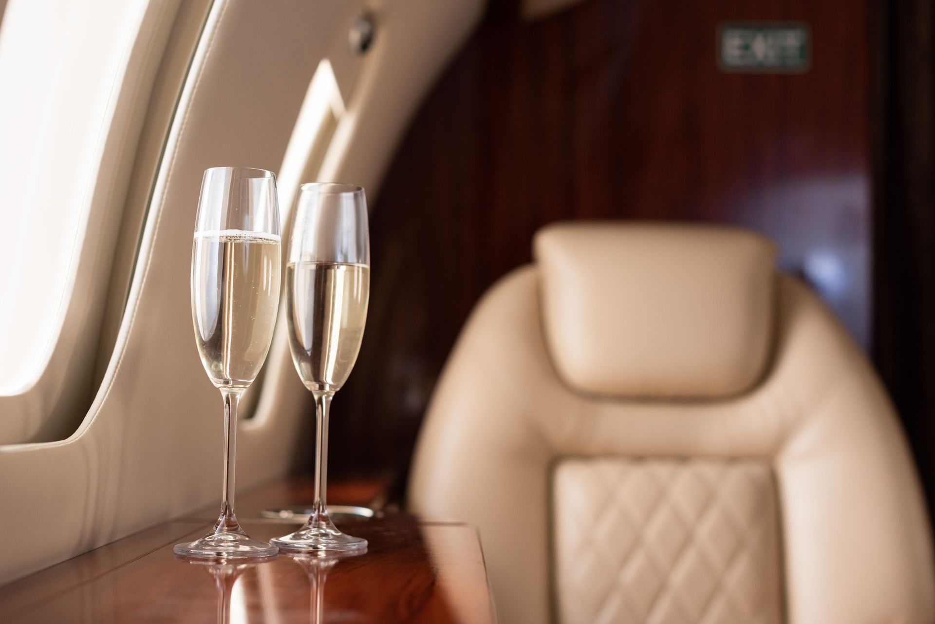 Two glasses of champagne are sitting on a table in an airplane.