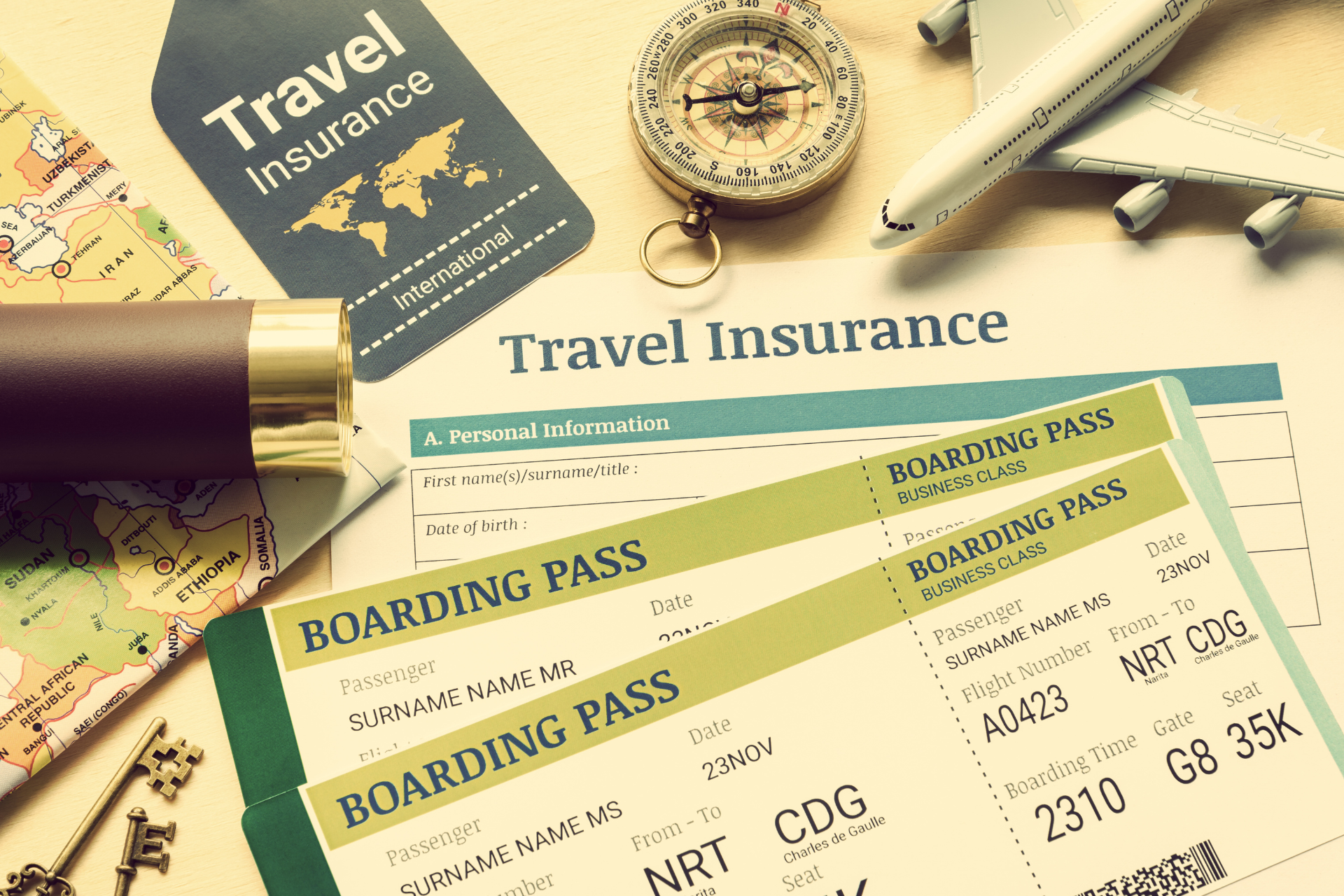 A travel insurance card , boarding pass , compass , and map are on a table.