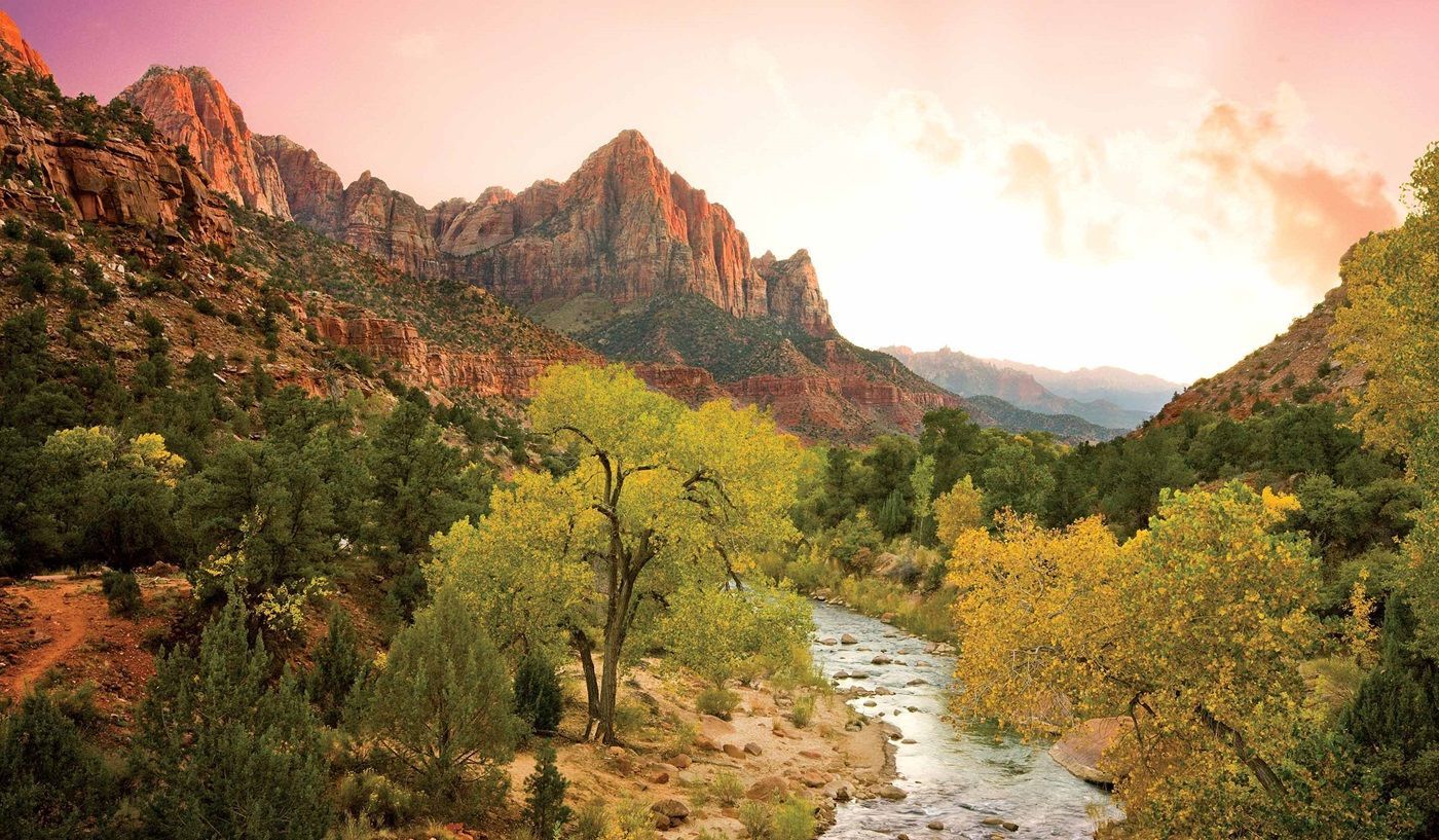 A river running through a valley surrounded by mountains and trees.