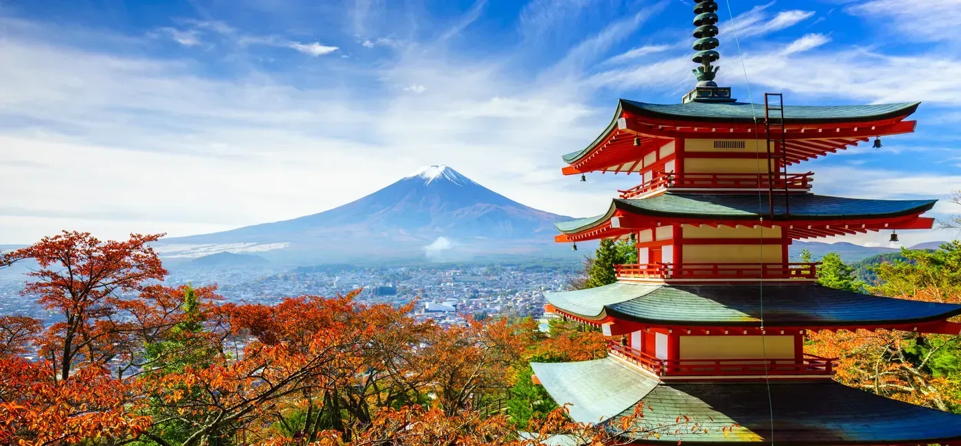 A pagoda with a mountain in the background and a city in the foreground.