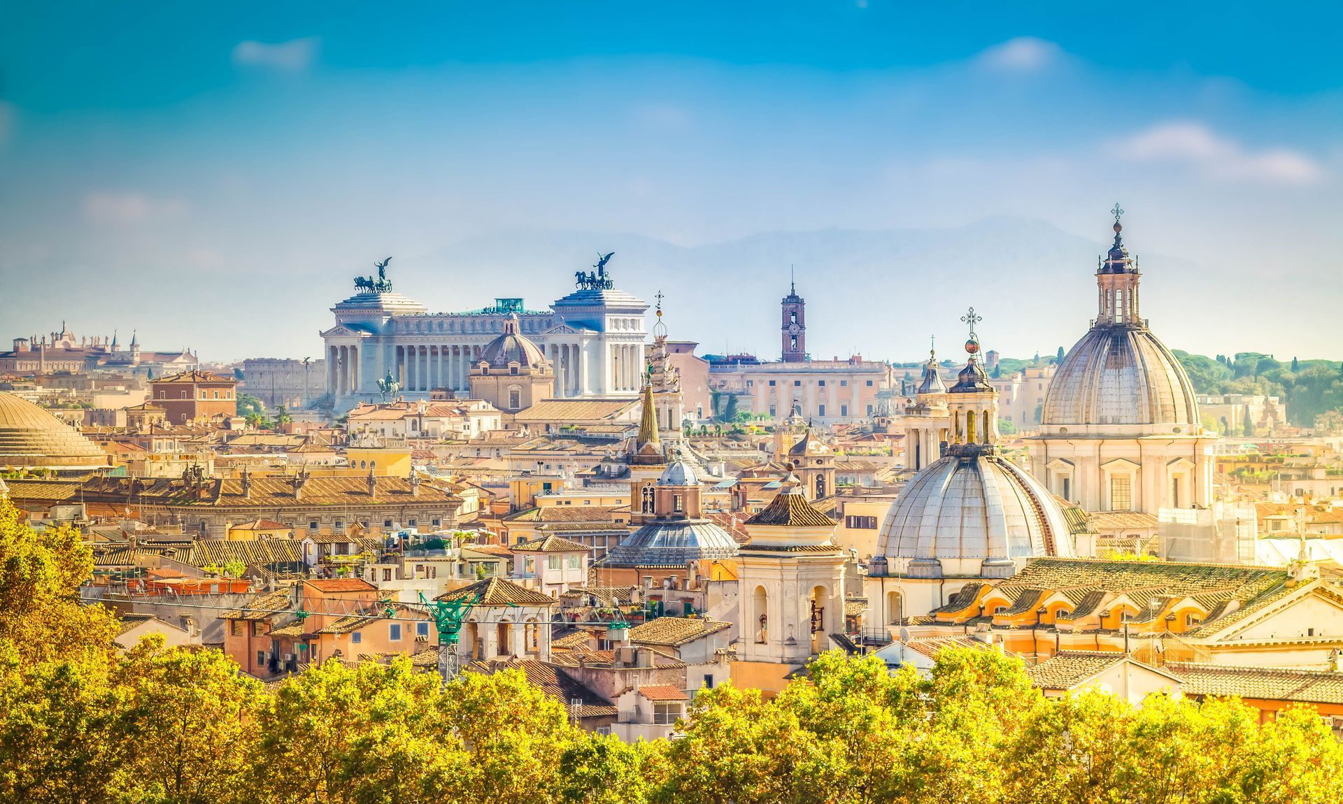 An aerial view of the city of rome with a lot of buildings and trees in the foreground.