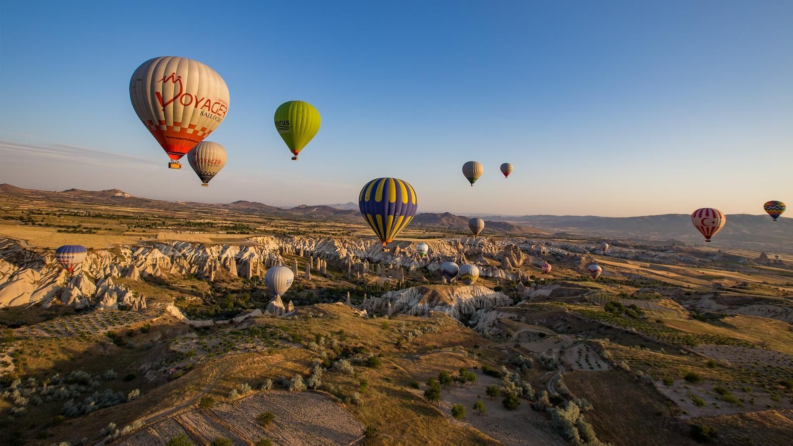 A group of hot air balloons are flying over a desert landscape.