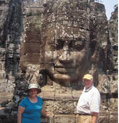 A man and a woman are standing in front of a large statue of a face.