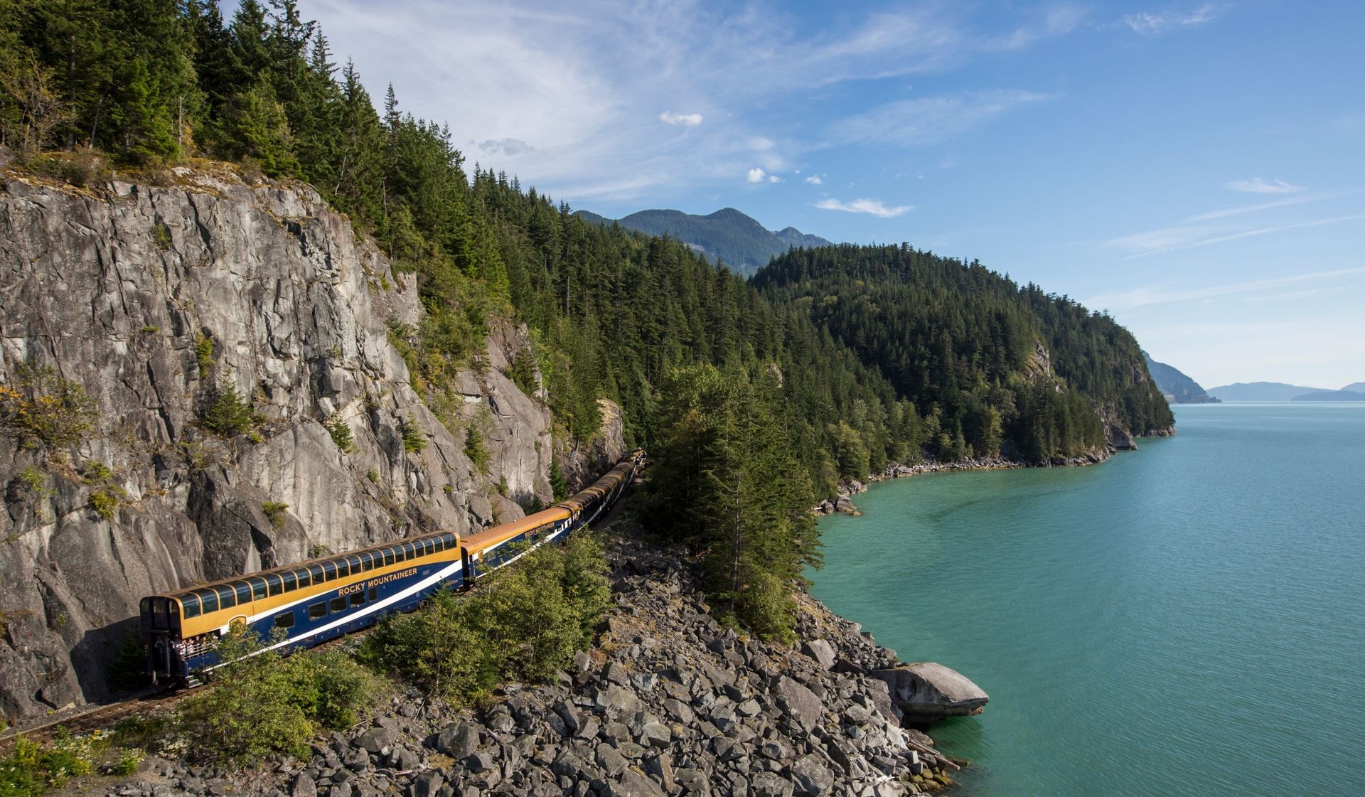 A train is going down a mountain next to a body of water.