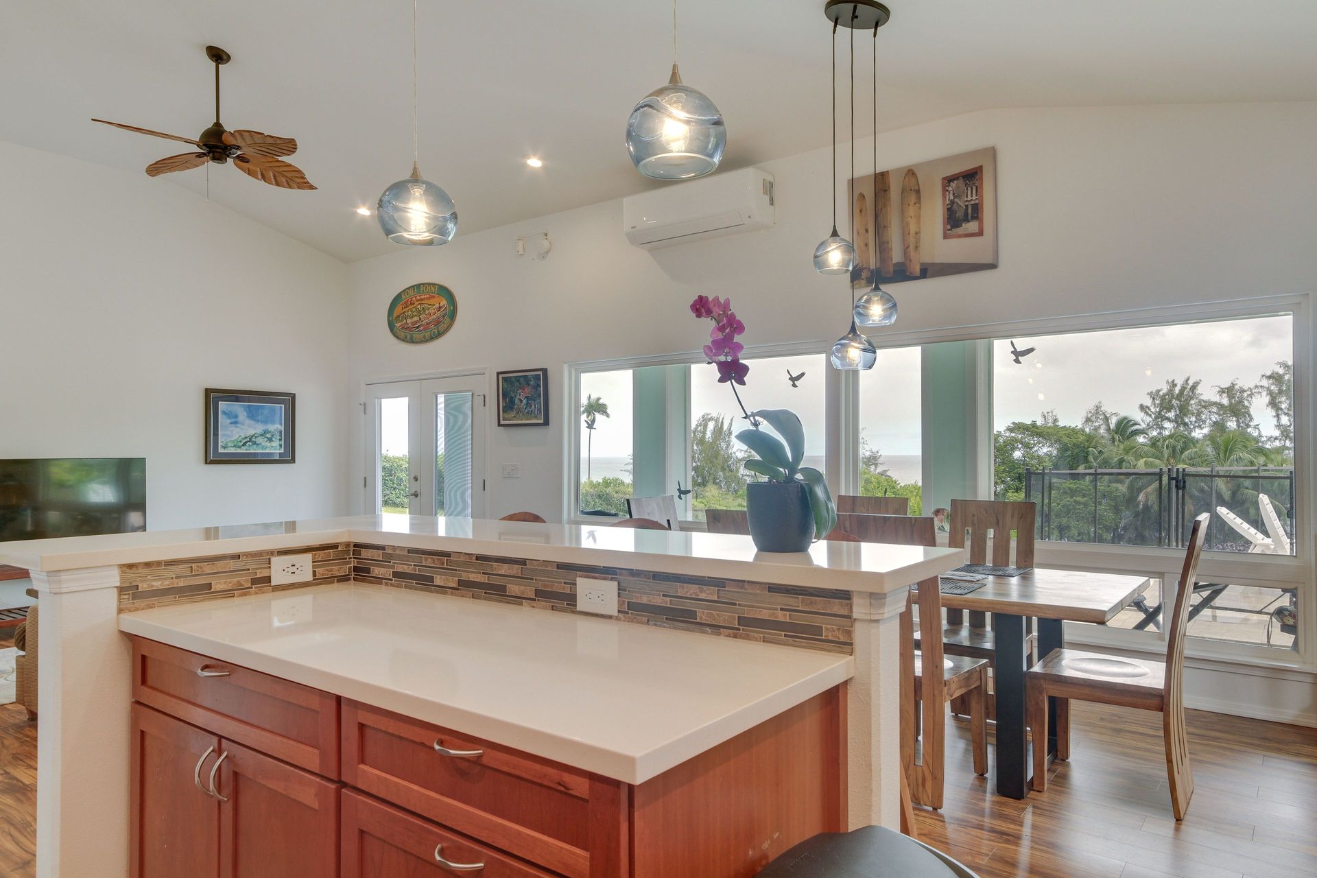 Open-concept kitchen with a white countertop island, pendant lights, and a dining area overlooking an ocean view.