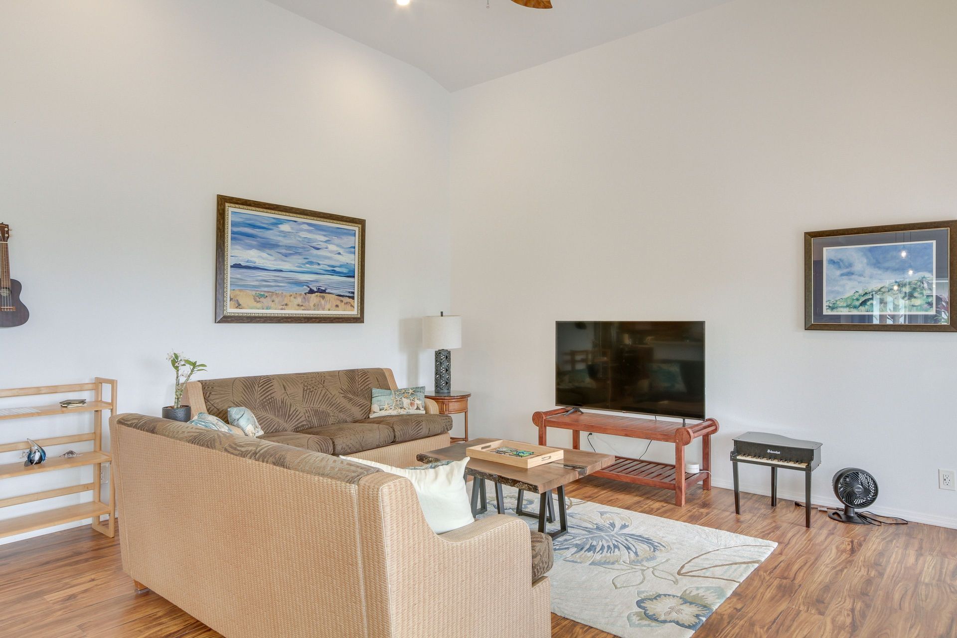 Living room with brown sofas, TV, artwork, and hardwood floors.