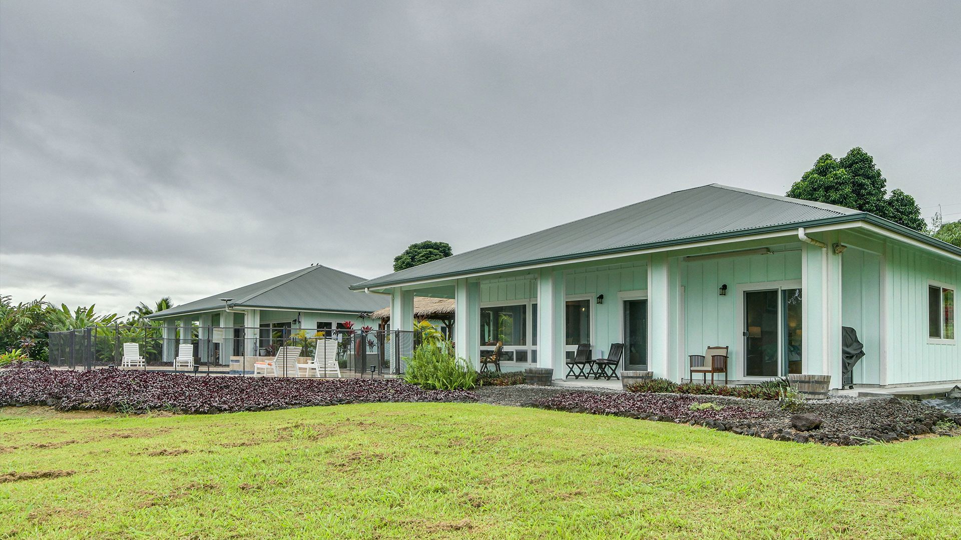 A house featuring a green roof and surrounded by a white picket fence.