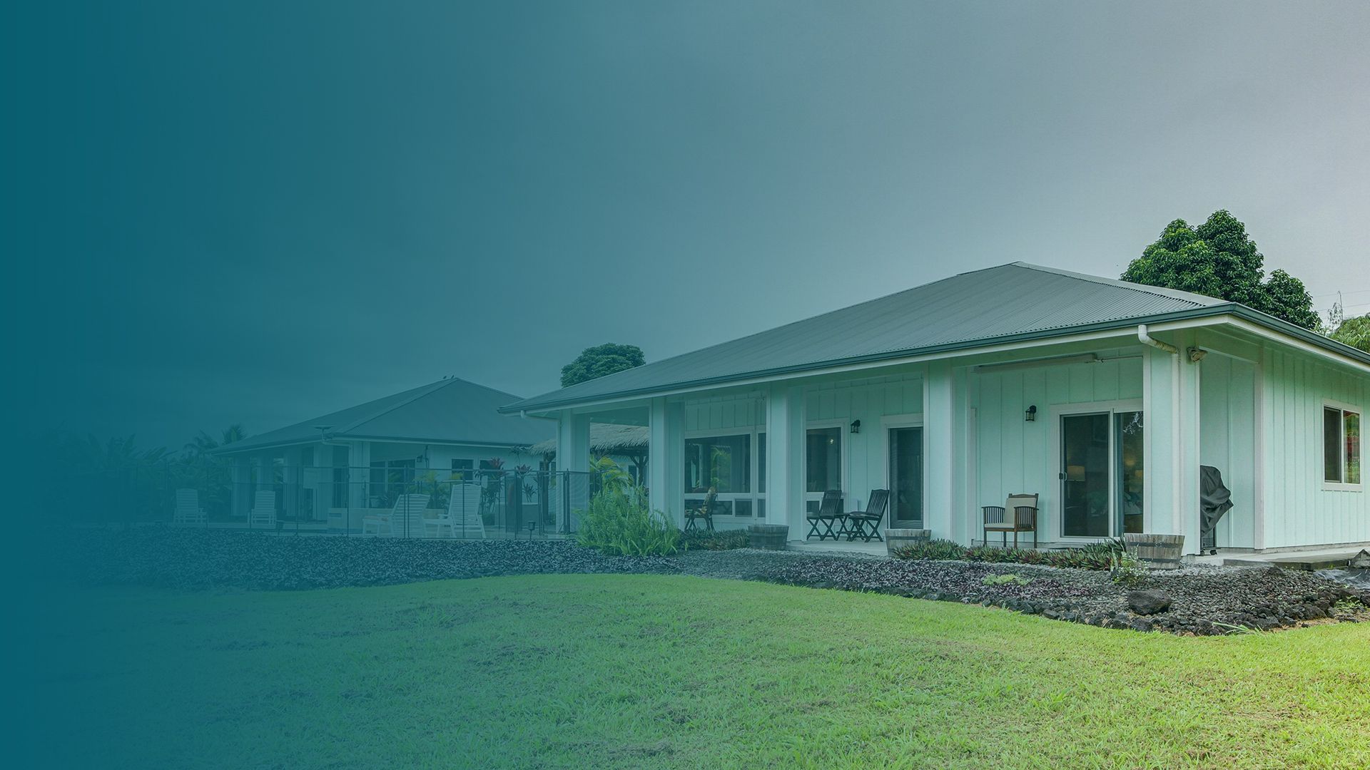 A house featuring a green roof and surrounded by a white picket fence.