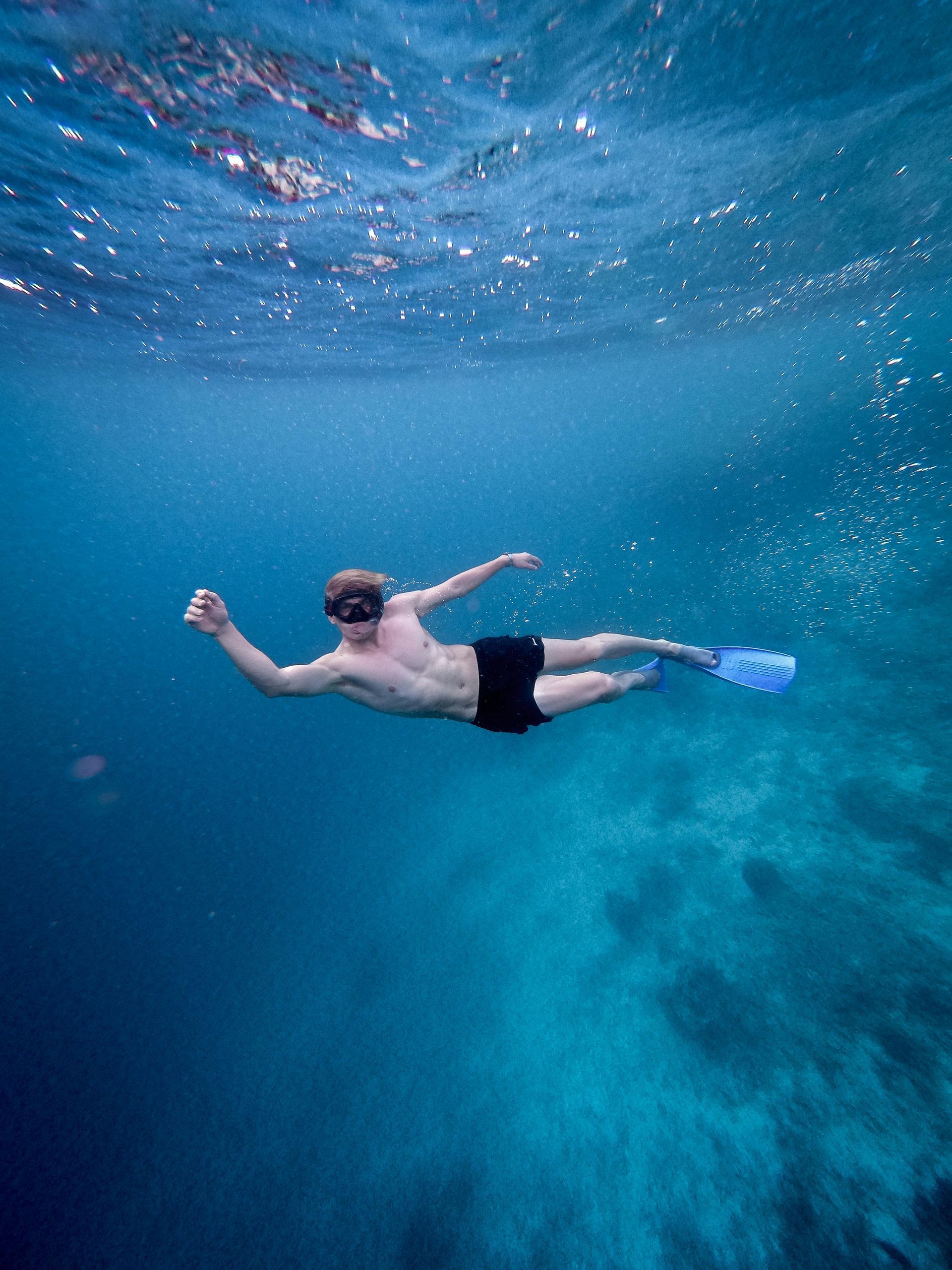 Man snorkeling underwater in blue ocean.