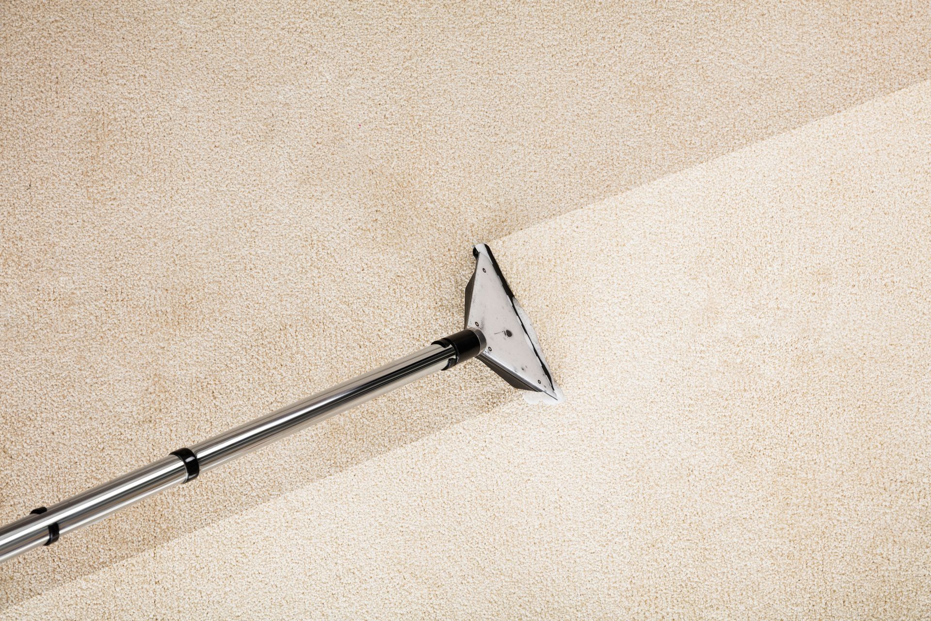 Professional carpet floor cleaning with vacuum cleaner on beige carpet in modern home interior.