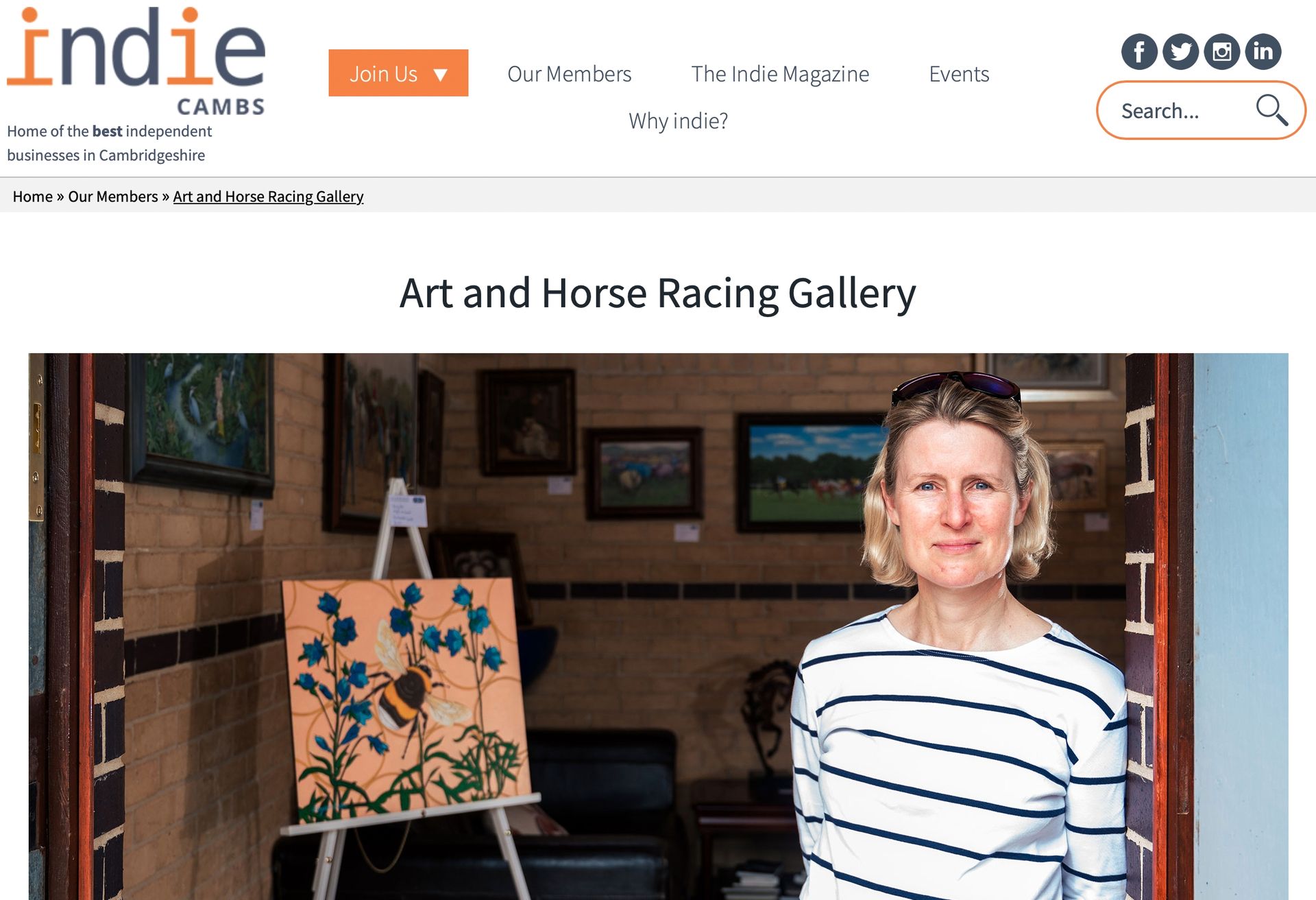 A woman is standing in front of a painting on an easel.