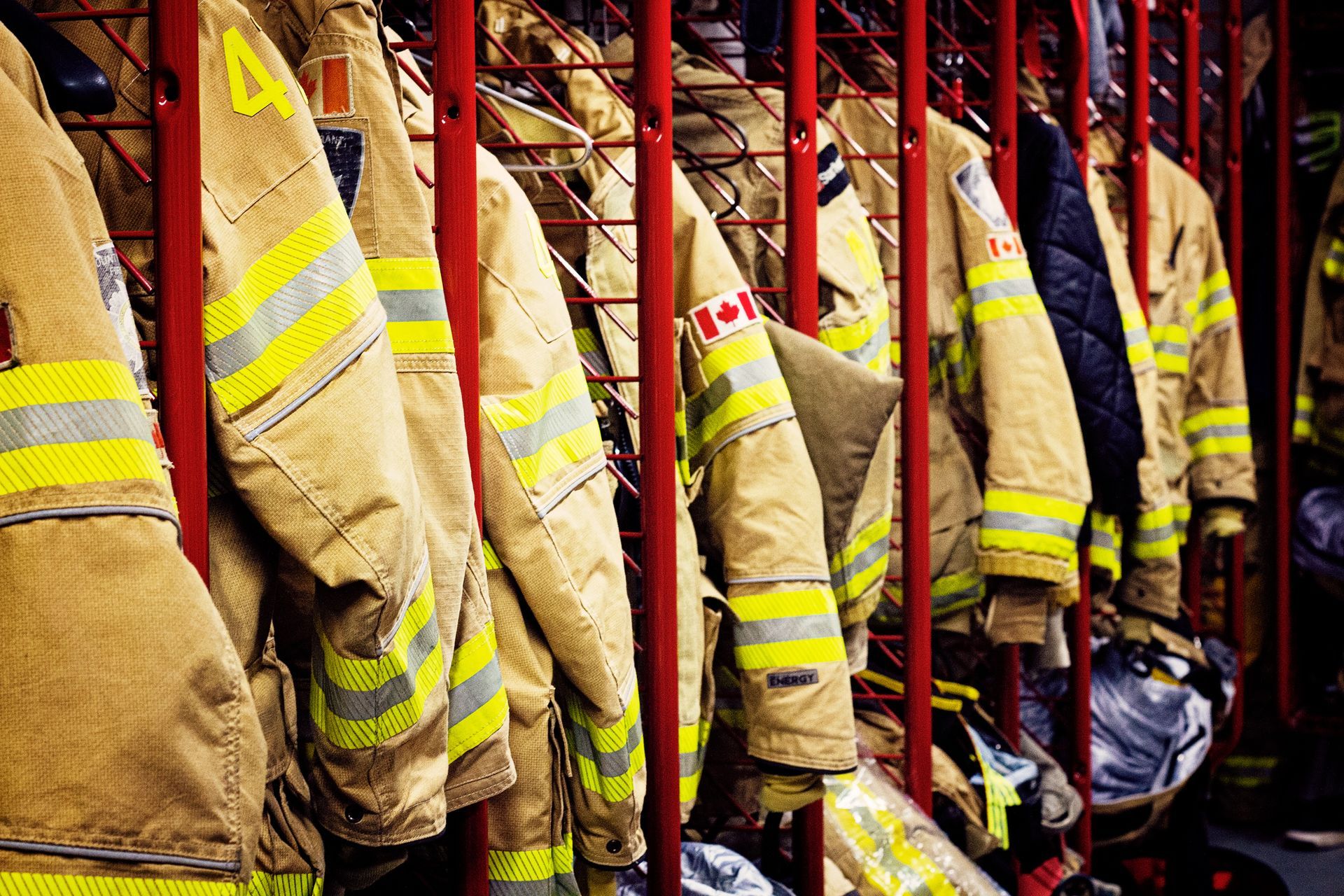 A row of firefighter 's uniforms hanging in a locker room.
