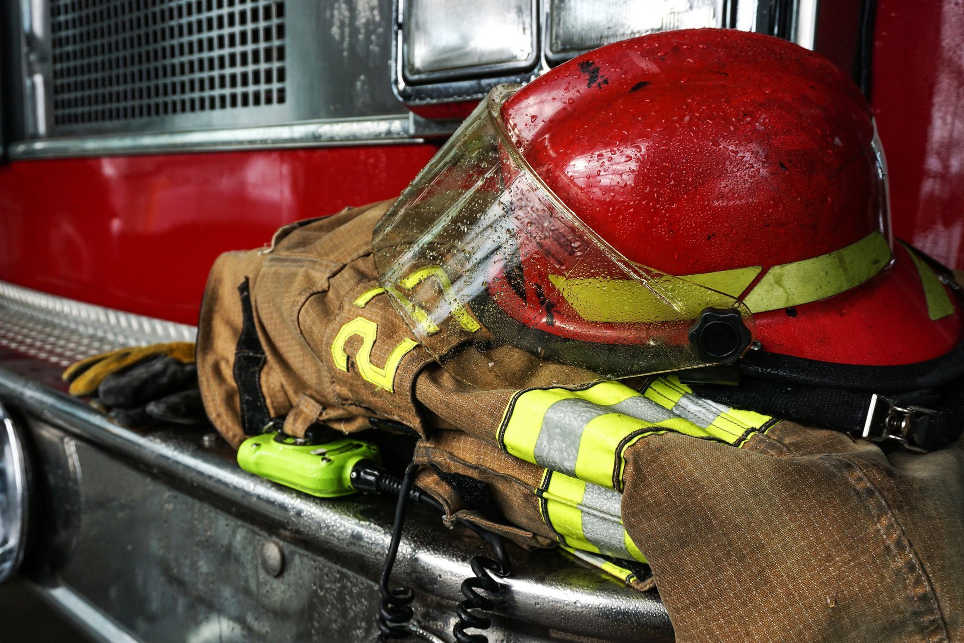 A fireman 's helmet and gloves are sitting on the side of a fire truck.