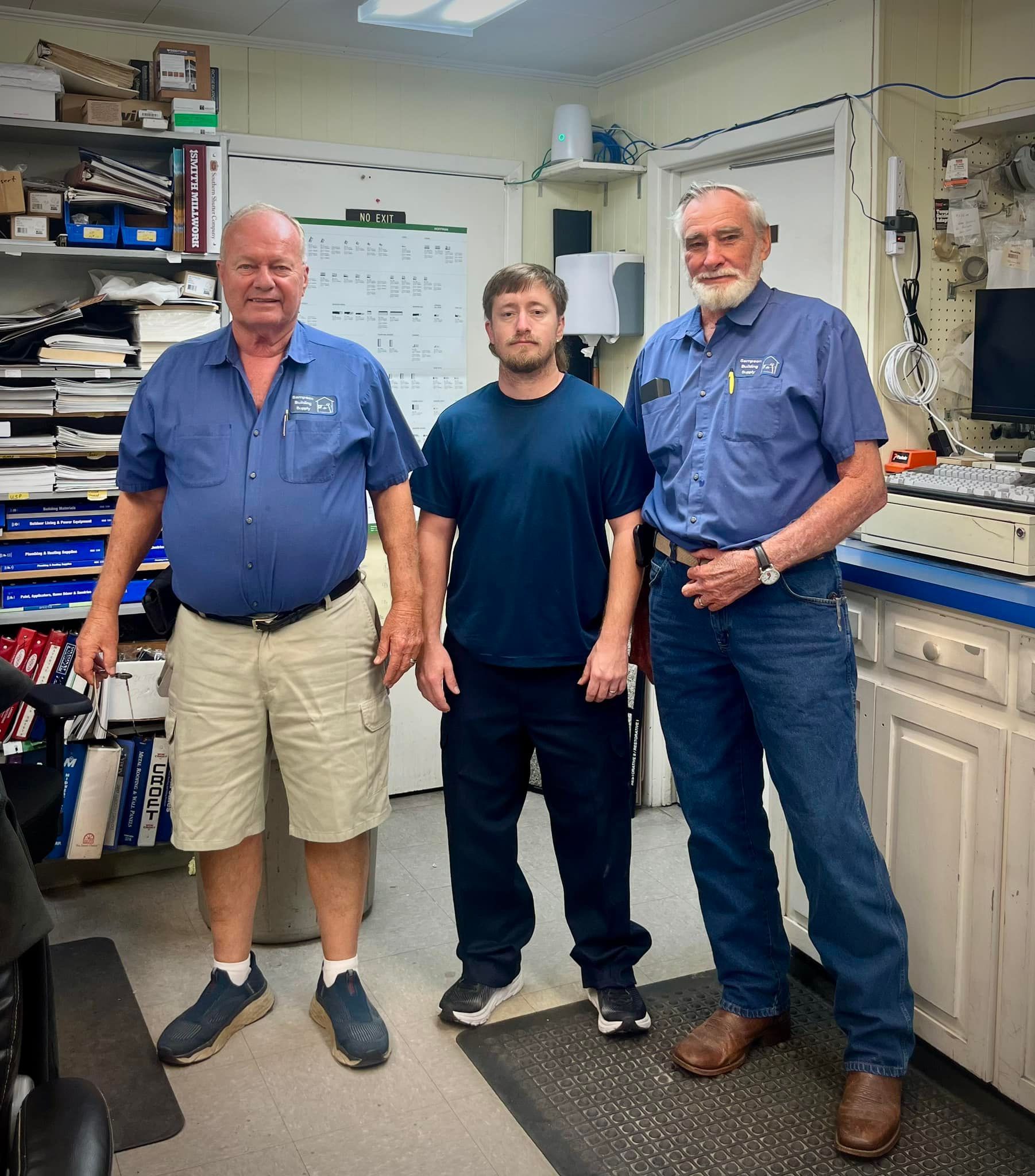 Three men are standing next to each other in a room.