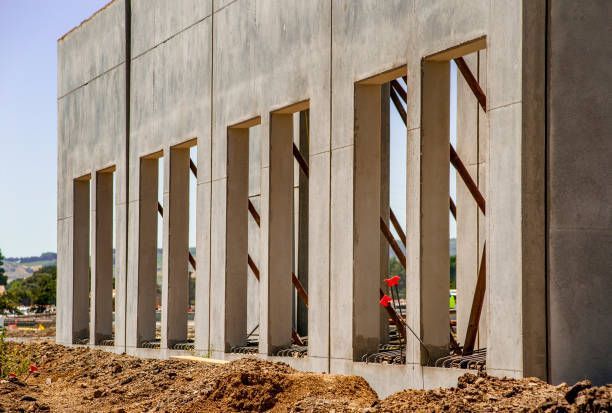 Concrete building under construction with rectangular openings and diagonal metal supports.