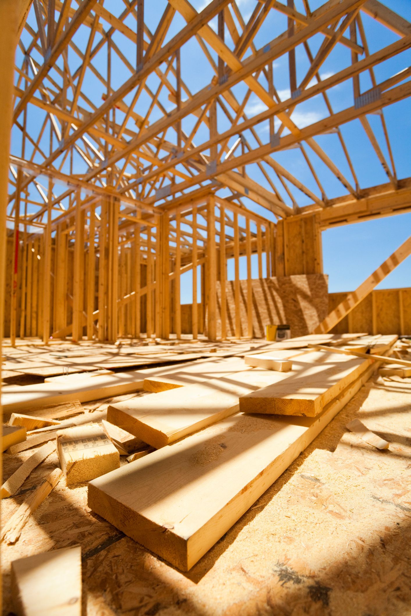 Wooden house frame under construction, with blue sky visible.