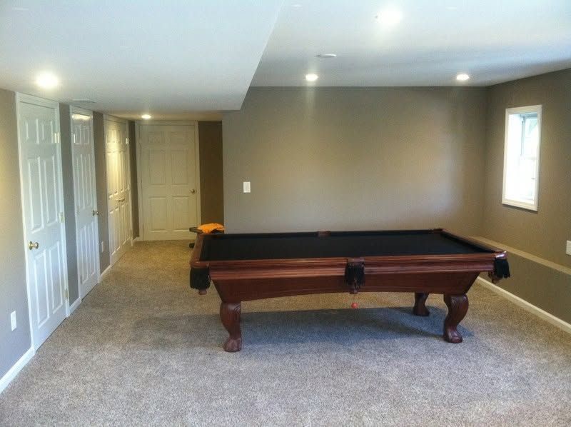 Game room with a pool table in a carpeted basement and a window on the right.