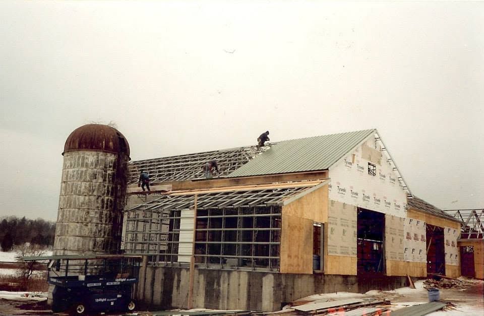 Barn and silo under construction in a snowy rural setting